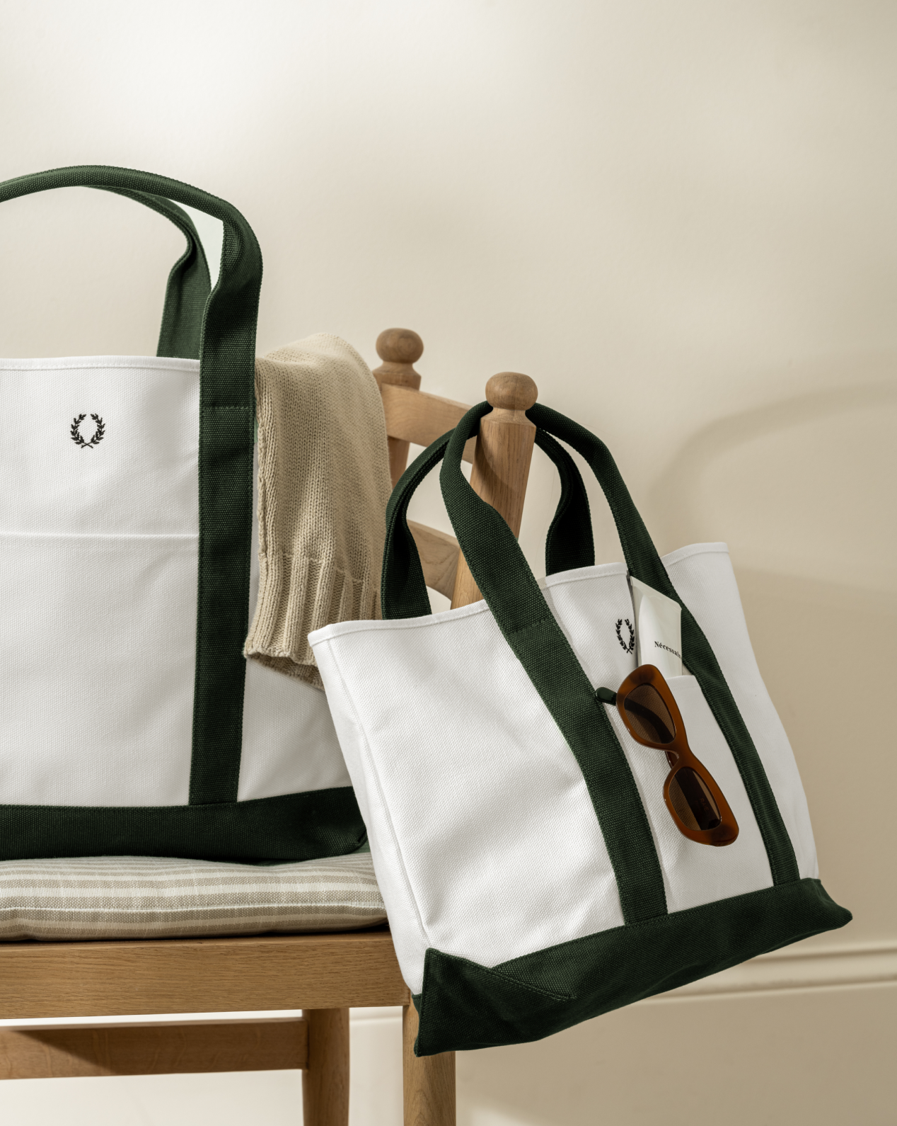 A sweater is draped over one everyday tote, while the Canvas Laurel Tote displays brown sunglasses hanging from its handle, by Vendixs