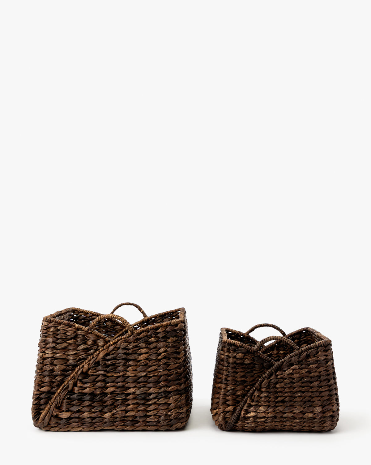 The Quimby Baskets (Set of 2) are rectangular, dark brown handwoven baskets with curved edges and handles, shown side by side against a white background, with the left basket larger than the right, by Vendixs