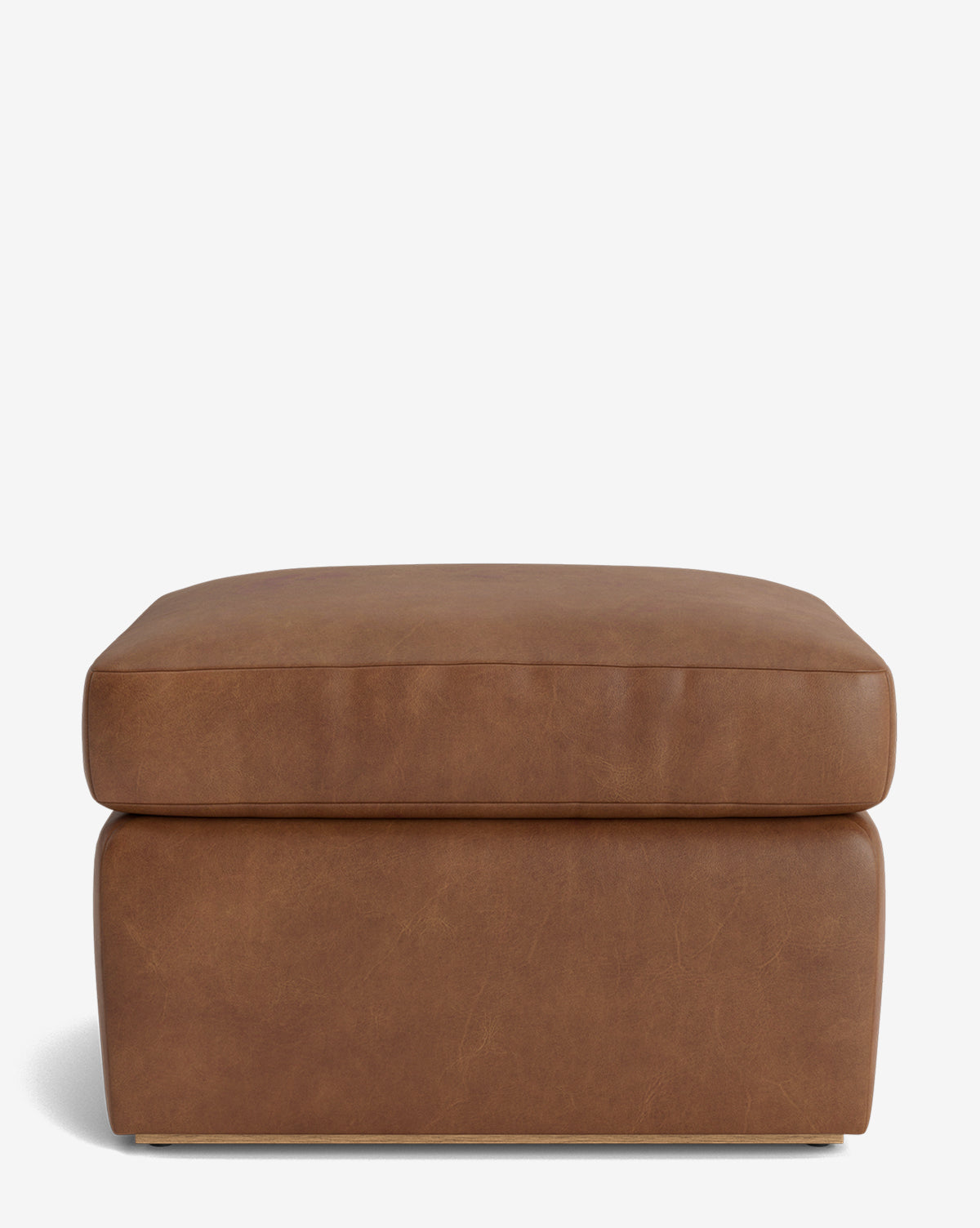 The Reese Ottoman is a handcrafted, square ottoman with brown leather and a down-wrapped cushion, showcasing a modern design against a plain white background, by McGee & Co.