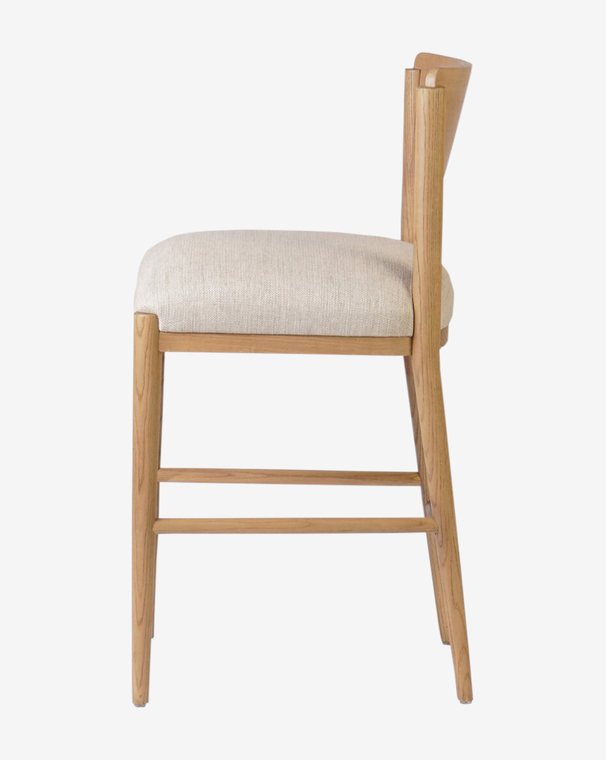 Side view of the Reverie Stool by Four Hands, a modern wooden chair for kitchens featuring a light beige cushioned seat, angled backrest, clean lines, and a natural wood finish. Vendixs
