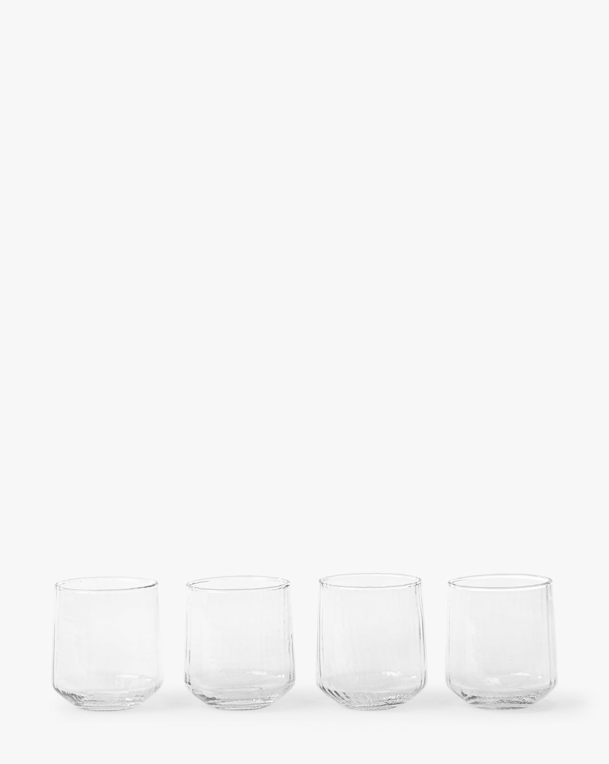 A set of four Ribbed Short Drinking Glasses is displayed in a row against a plain white background, by McGee & Co.
