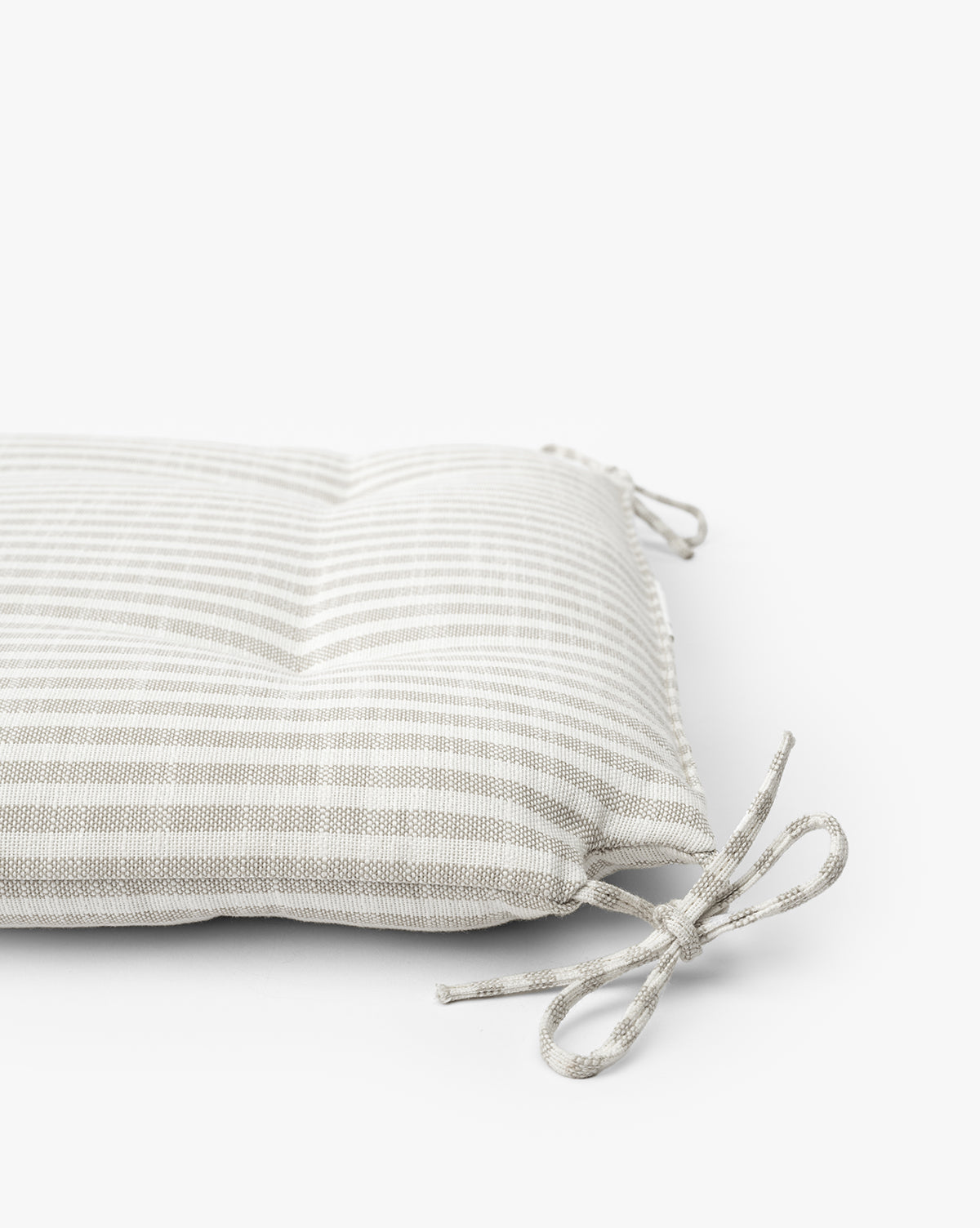 A close-up of the Credence Romany Dining Chair Cushion, featuring light gray and white stripes with two fabric ties, perfect for oak dining chairs, set against a plain white background. Vendixs