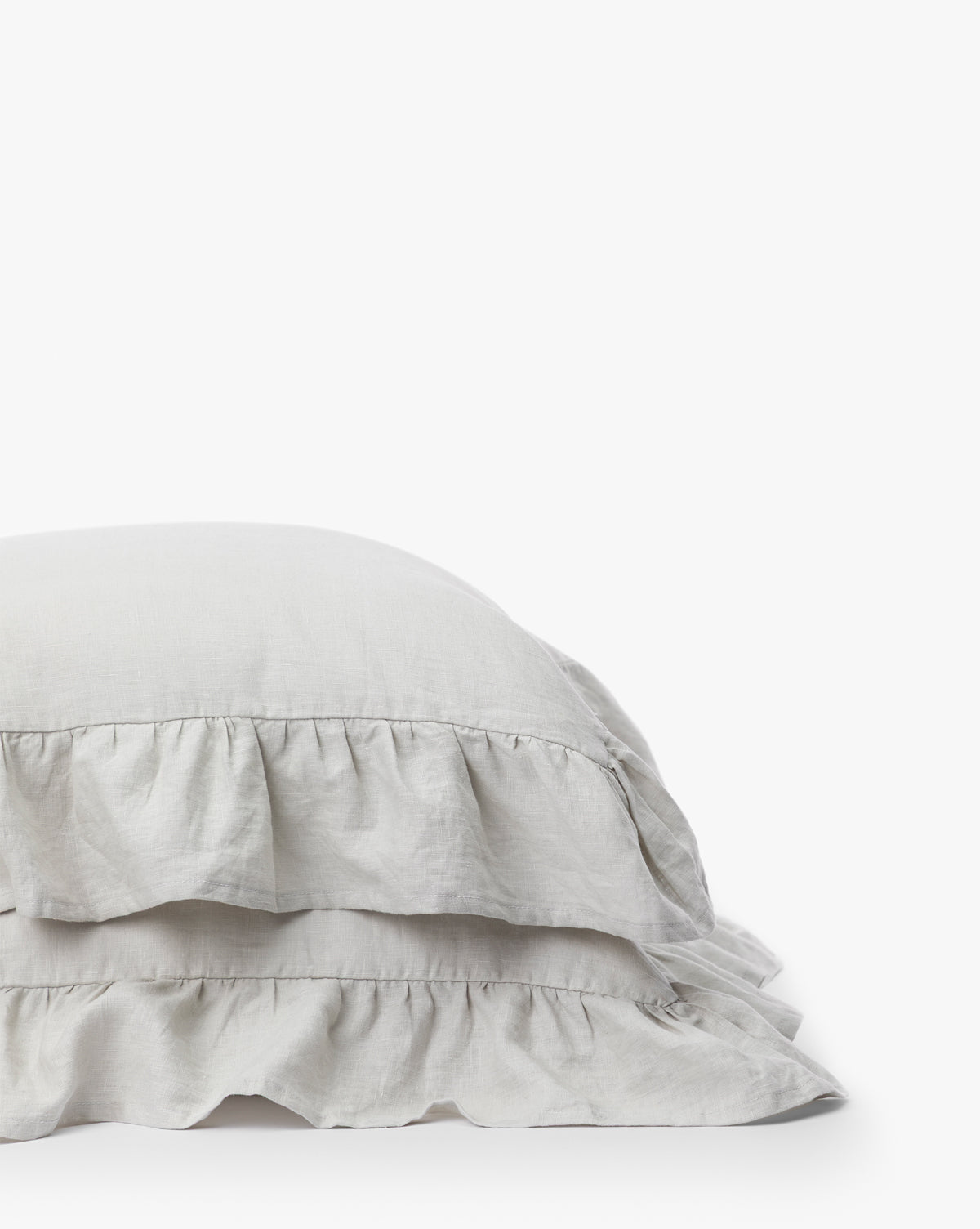 The Ruffle Linen Shams (Set of 2) in light gray feature elegant ruffled edges, stacked on a white surface against a plain background—ideal for adding a romantic touch to your bedding.