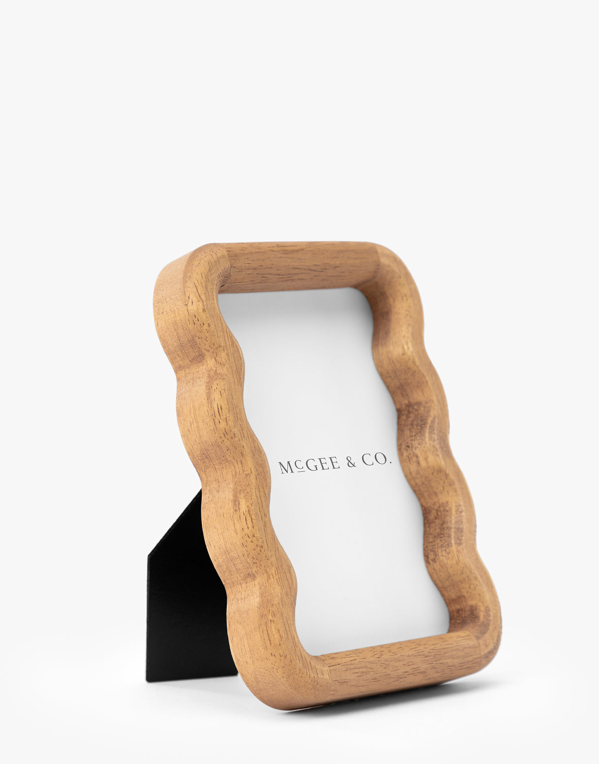 The Scalloped Wood Frame, made from natural rubberwood with a wavy edge and support stand, adds timeless elegance to any space. It displays a paper reading Vendixs on a white background by Vendixs