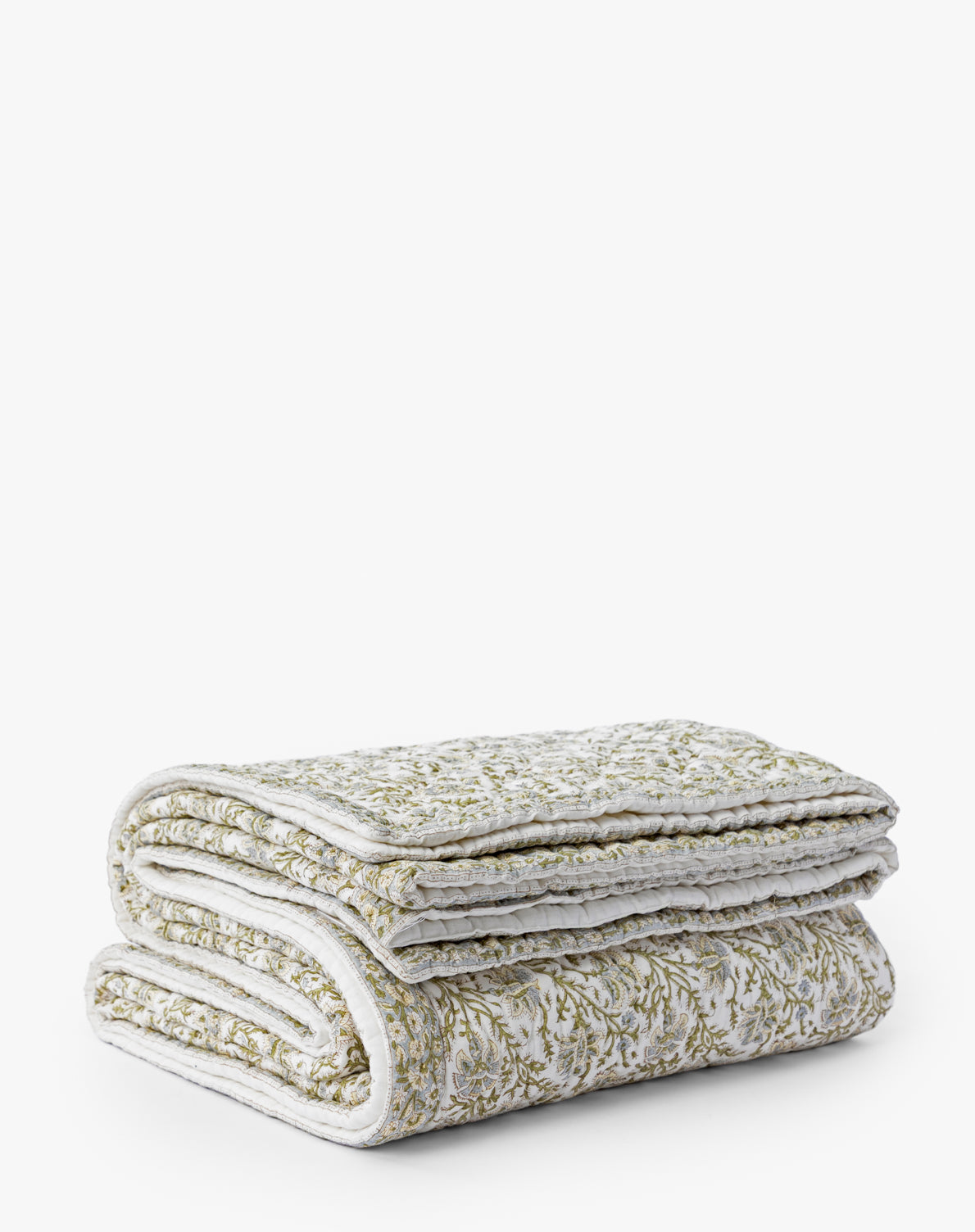 The Seton Kids Quilt by Renuka Inc. is a neatly folded, quilted blanket featuring a subtle white and green floral pattern, shown against a plain white background — Vendixs