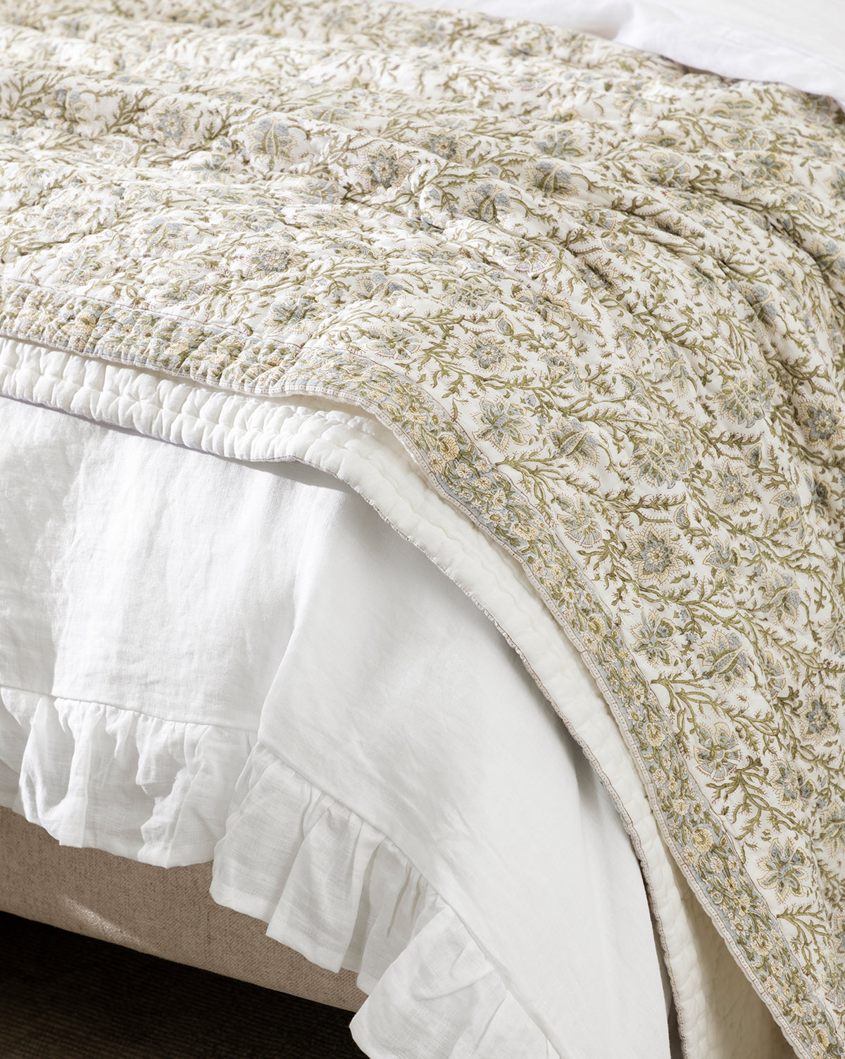 The Seton Kids Quilt features delicate vine patterns in earthy green and beige tones, and is paired with a white ruffled bed skirt for a charming, nature-inspired look, by Vendixs