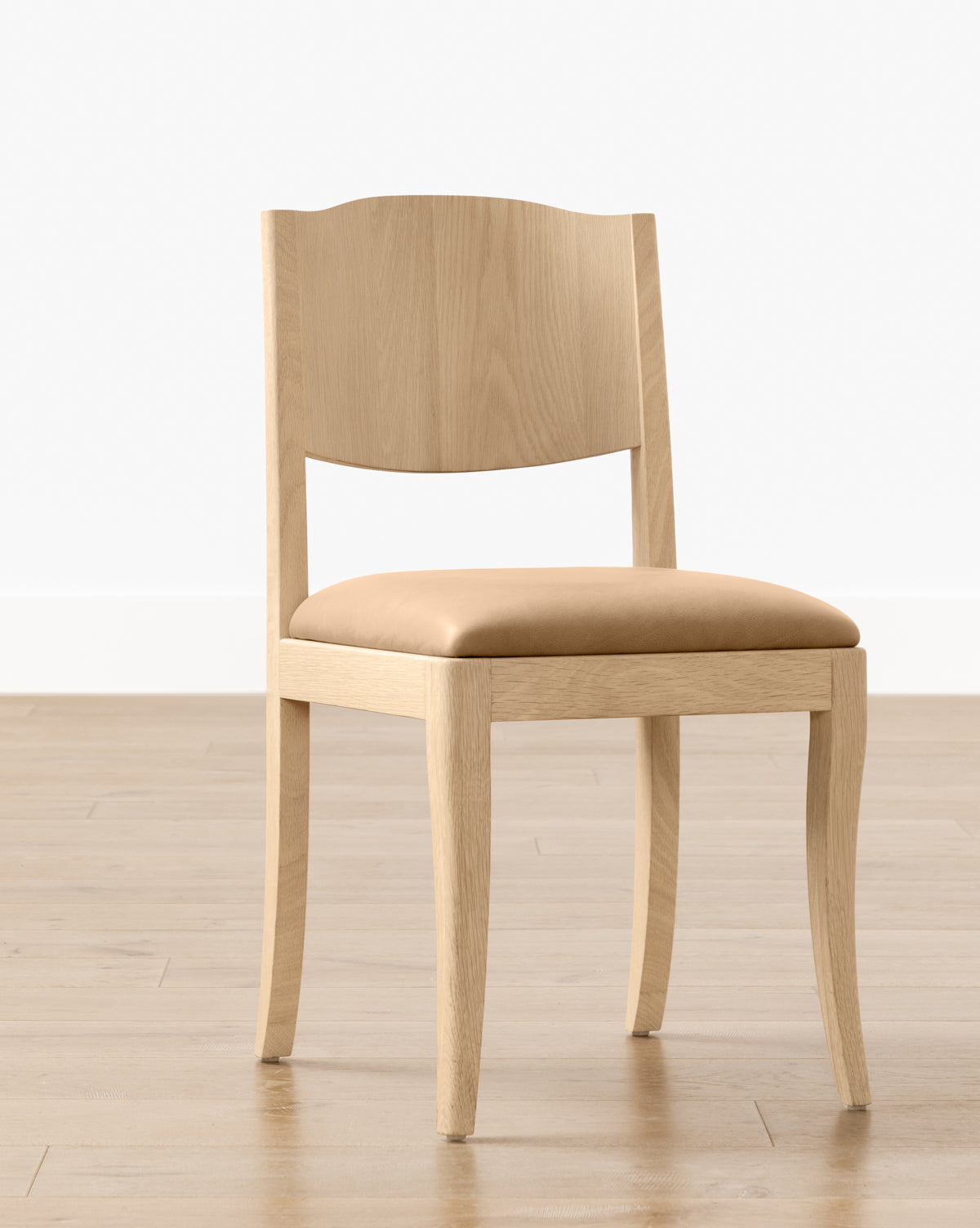 The Shepherd Dining Chair, featuring a white oak frame and a tan upholstered seat cushion, is placed on a light wood floor with a plain white wall in the background, by Vendixs