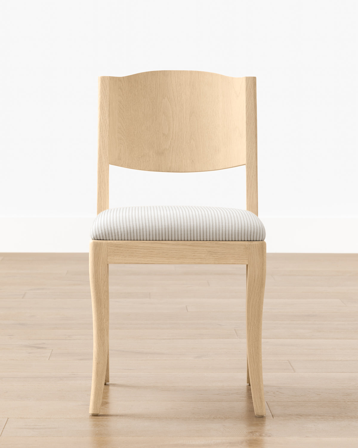 The Shepherd Dining Chair has a light wood, white oak frame with a curved backrest and an upholstered seat in light gray and white stripes, shown on a wooden floor with a white wall by McGee & Co.