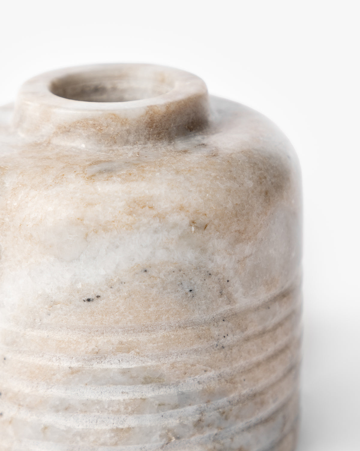 Close-up of the upper part of the Stinson Marble Bud Vase—a small, round beige and white vase with subtle veining and horizontal etched lines near the base—set against a plain white background, by Vendixs
