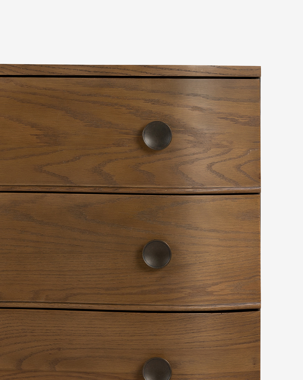 Close-up of the Strasburg Nightstand, a wooden dresser with a natural finish and three drawers. Each drawer features a round, dark metal knob handle. Perfect for bedroom styling and resembles an antique nightstand, by McGee & Co.