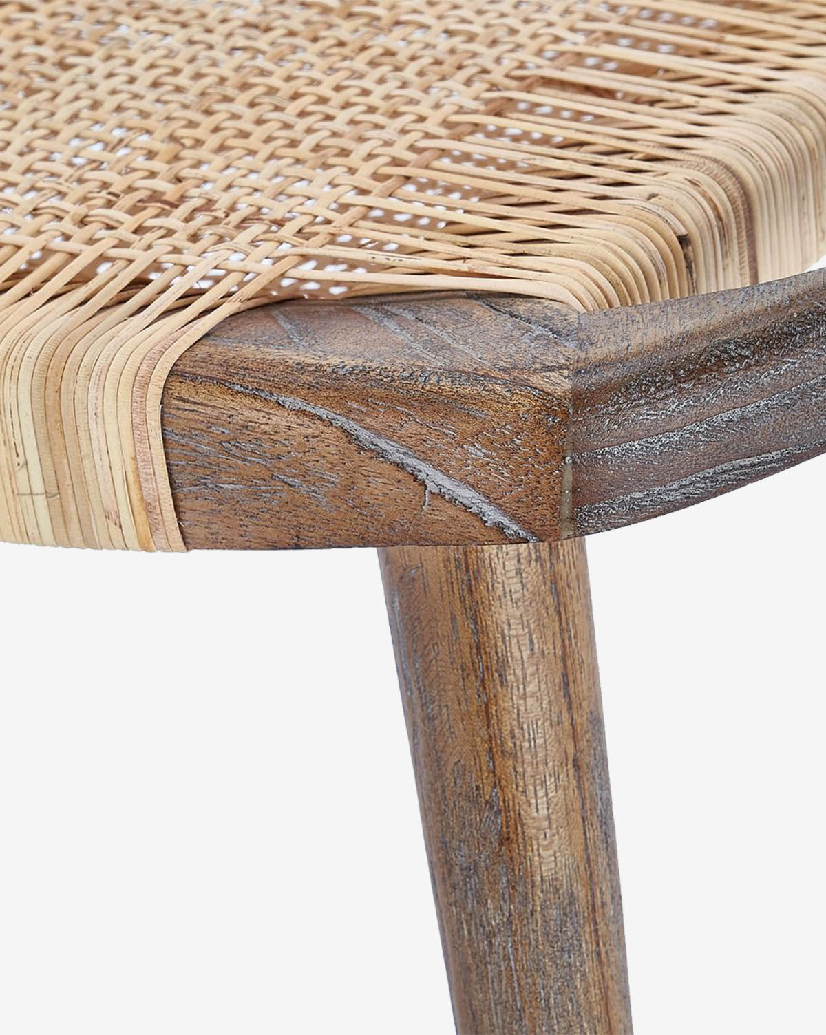 Certainly! Here’s your blended product description: Close-up of a Tallulah Stool by Villa & House, LLC, showing a corner and leg with handwoven cane seat in natural finish. The mahogany wood features a weathered, rustic look and distinctive grain patterns. Vendixs