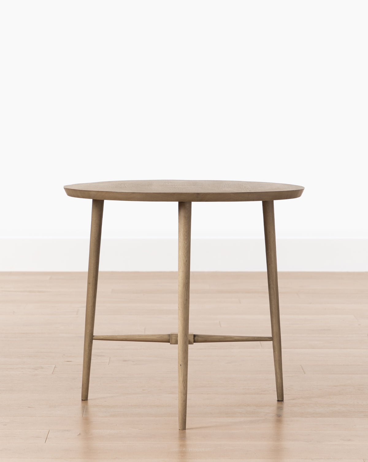 The Tavin Side Table, made from solid white oak with four slender legs and a crossbar support, stands on a light wood floor against a plain white background.