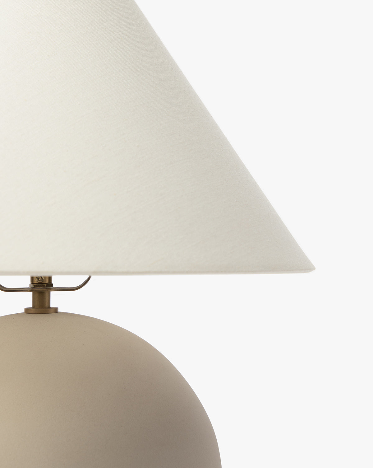 A close-up of the Tess Ceramic Table Lamp, featuring a matte beige rounded ceramic base and a white fabric shade, set against a plain white background, by Vendixs