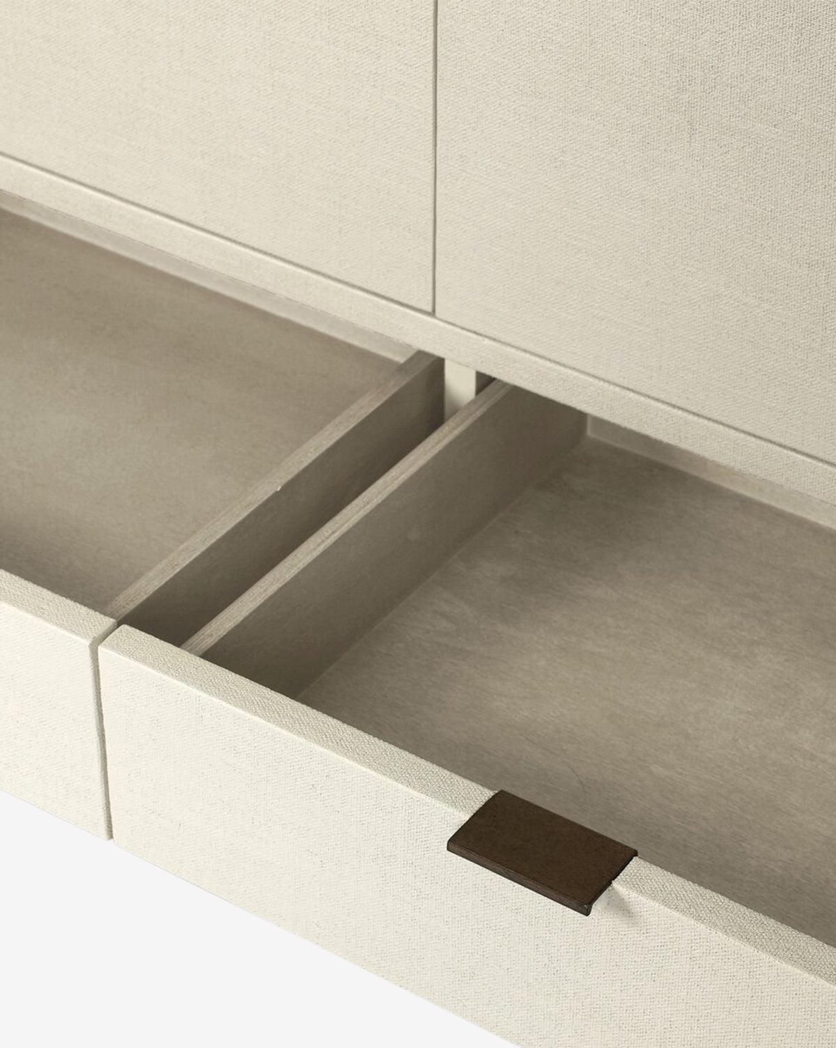 A close-up of an open beige drawer in the Thaddeus Cabinet, featuring a fabric-like texture, central divider, and brown rectangular pull tab—showcasing extra storage with modern classic style, by Vendixs