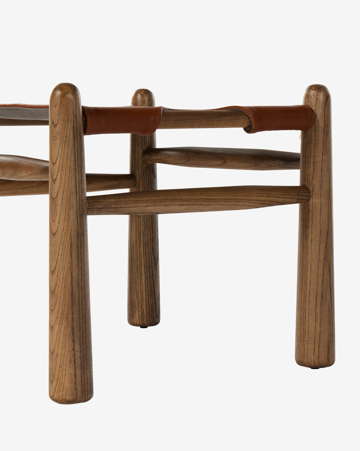A close-up of the Tierney Ottoman by Four Hands highlights its solid wood frame with rounded legs, top grain leather seat, smooth wood grain, and minimalist design. Vendixs