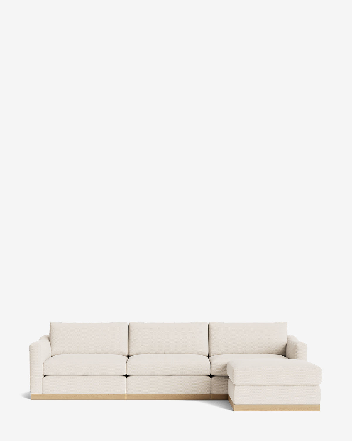 The Vernon Modular Sofa with Ottoman 121 is a modern, light beige sectional with three seats, a right-side chaise lounge, boxy cushions, and a low wooden base, shown against a plain white background by McGee & Co.