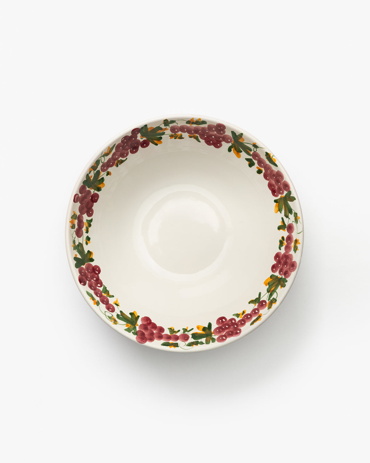 The Vine Large Bowl is a handmade ceramic piece with a decorative rim of red berries, green leaves, and a grapevine motif, seen from above on a plain white background—ideal for enhancing any table setting, by Vendixs