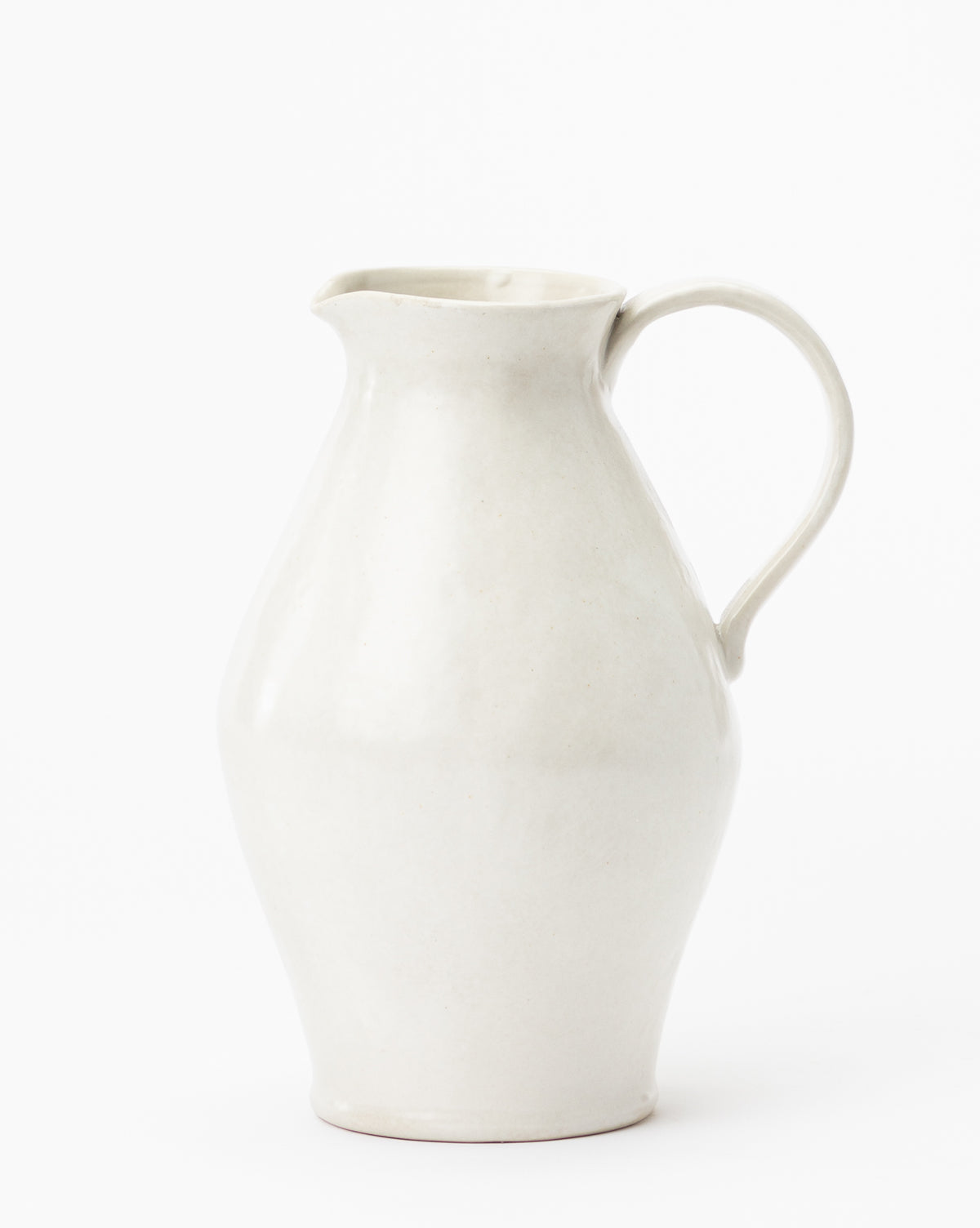The White Ceramic Pitcher features a curved body, wide spout, and single handle with a smooth matte finish, set against a plain white background, by McGee & Co.