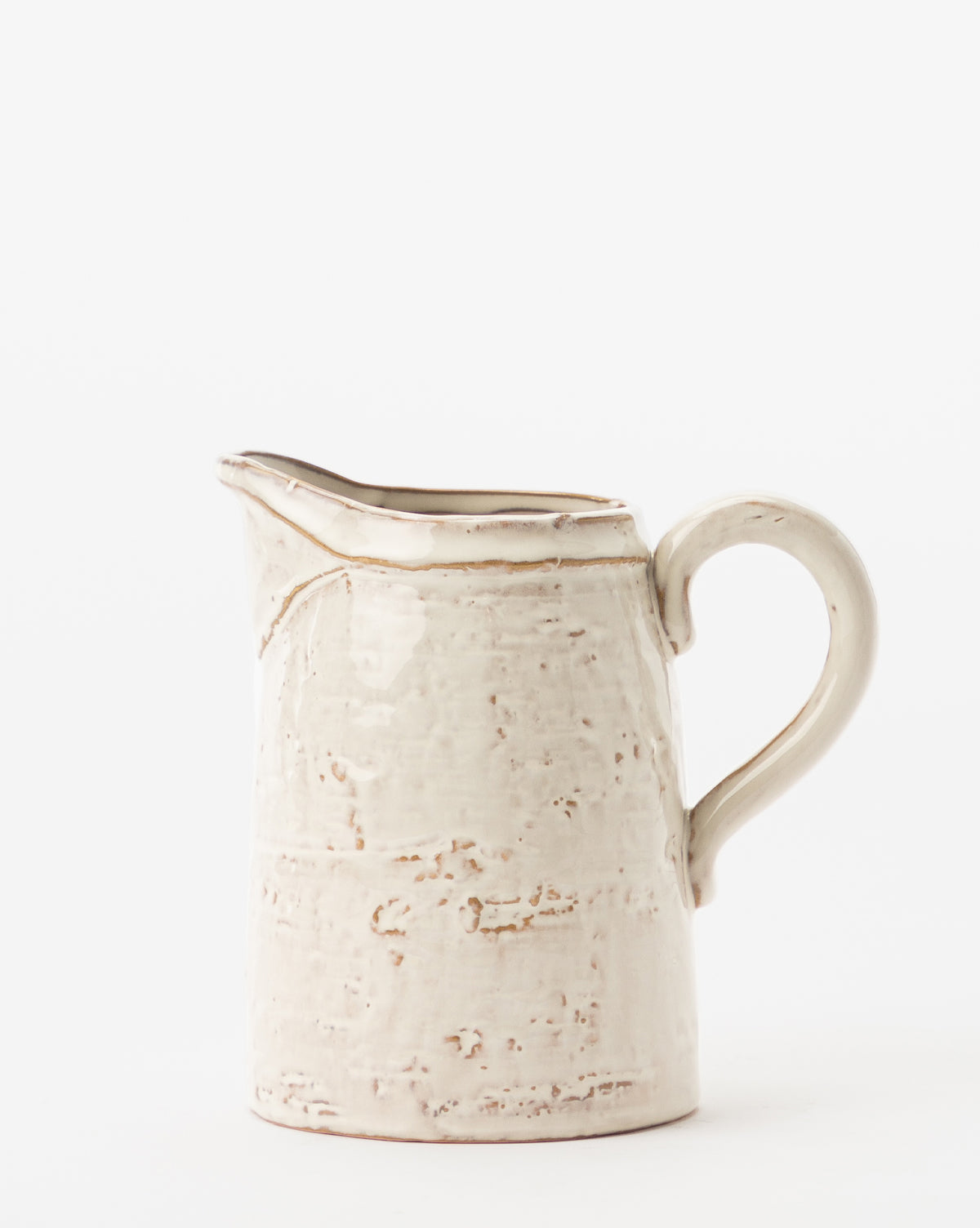 The White Stoneware Pitcher features a cream color, textured rustic surface, and curved handle, shown against a plain white background, by Vendixs