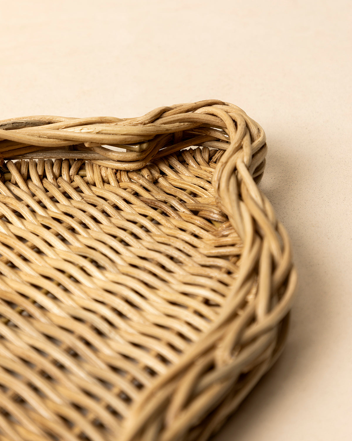 Close-up of the Wicker Bell Tray, featuring braided edges and intricate handwoven texture, set on a light beige surface—ideal for adding elegance to your holiday entertaining setup, by Vendixs