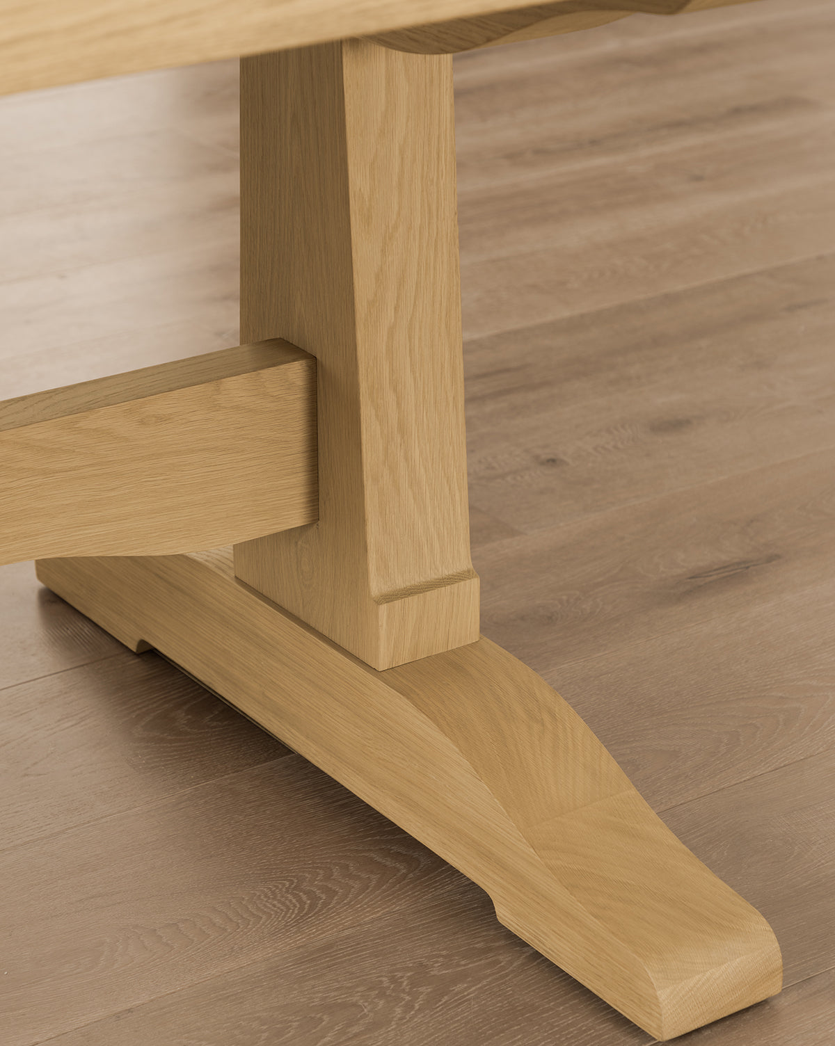Close-up of the Wilton Dining Table’s wooden base and leg on a light wood floor, showcasing the grain and texture of its natural white oak finish, by Vendixs