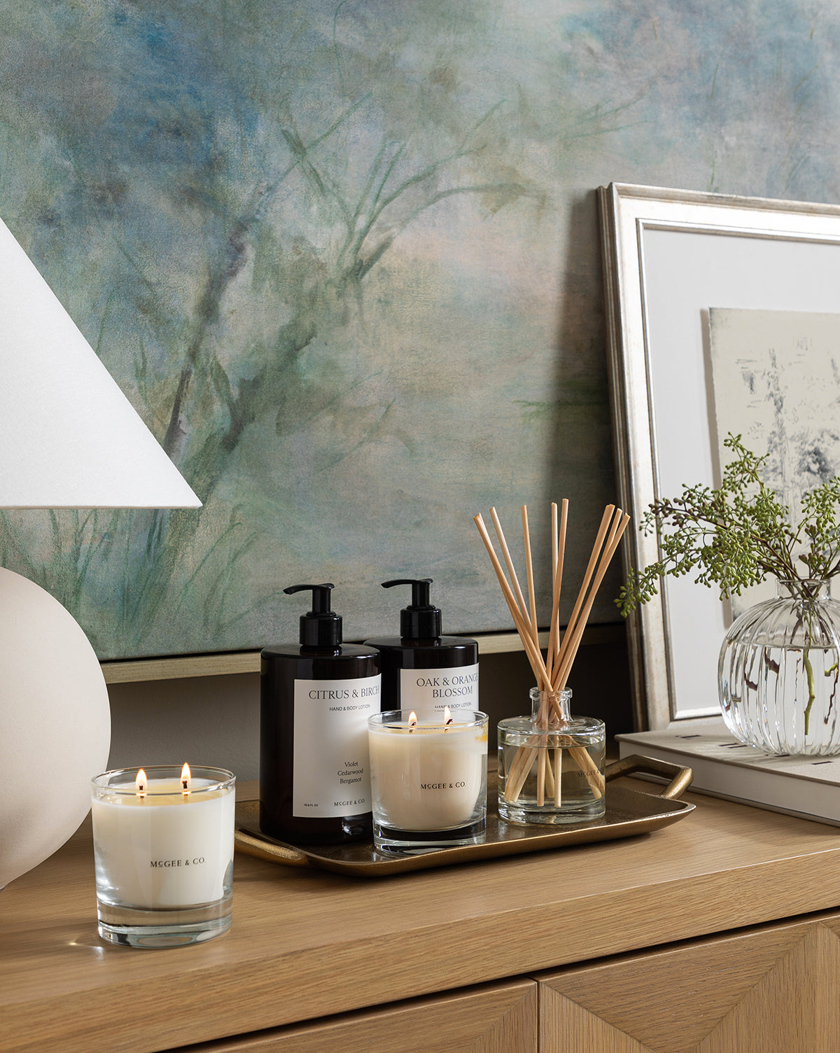 The Oak & Orange Blossom Candle adds a warm glow beneath a large abstract painting, by Vendixs