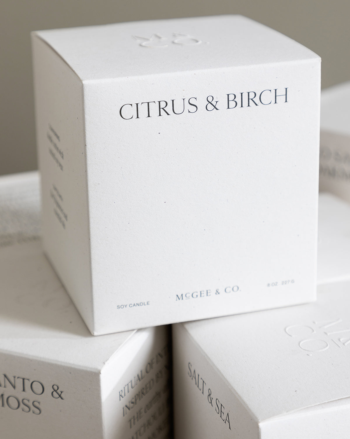 A close-up of the minimalist Citrus & Birch Candle box, crafted from soy wax, with other luxury candle boxes partially visible in the background, by Vendixs