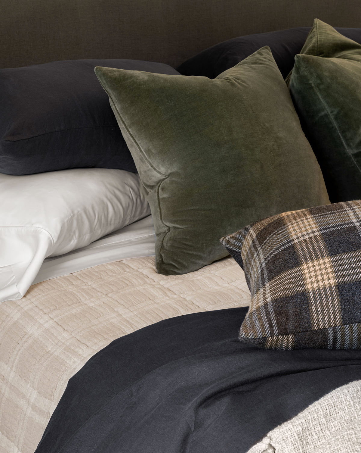 A bed with a soft cotton pillow and a stone washed velvet pillow, both topped with elegant Bellevue Velvet Pillow Covers, by McGee & Co.