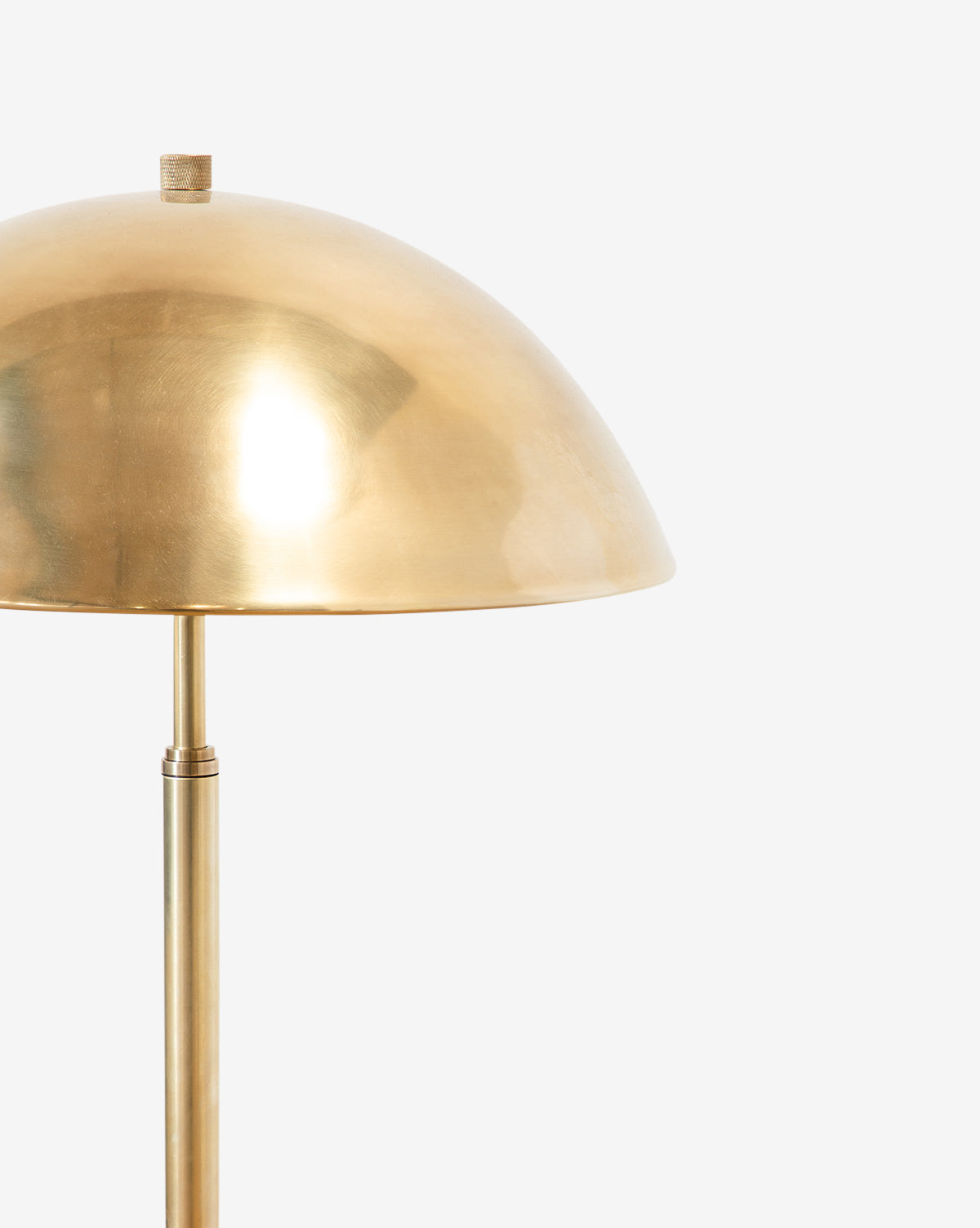 A close-up of the Aldorno Floor Lamp featuring a modern design with a shiny, dome-shaped brass shade and a matching straight brass stand, shown against a plain white background, by Vendixs