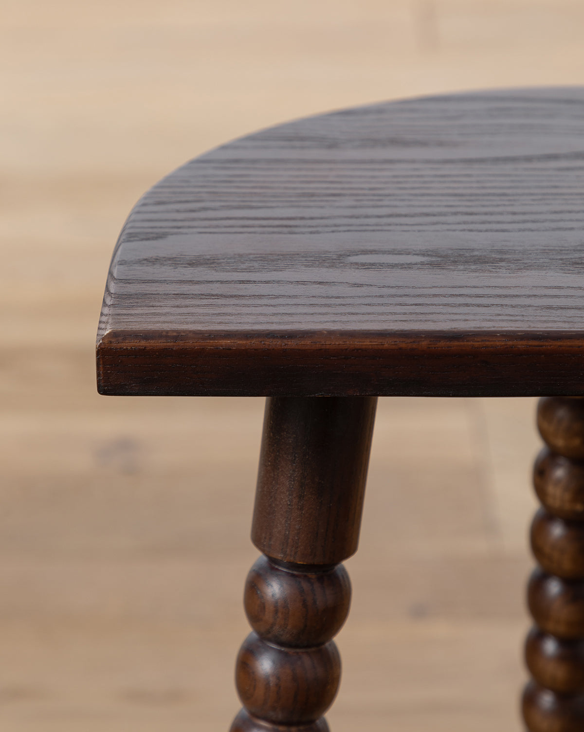 Close-up of the Alice Wood Stool, crafted in ash with polished, rounded edges and beaded, turned legs, set on a light wooden floor for a vintage-inspired look, by Vendixs