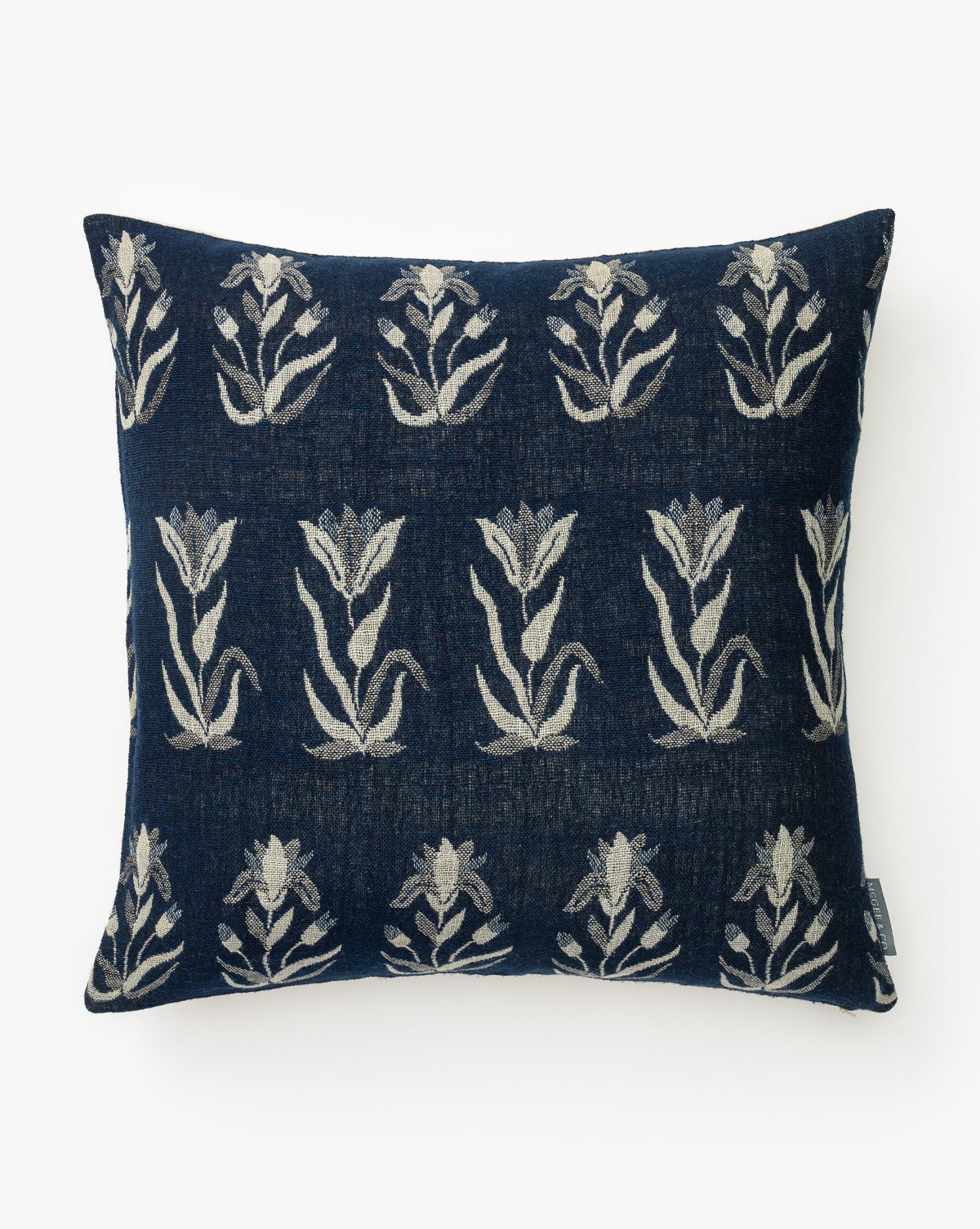 The Annika Pillow Cover is a square, navy blue cover with light beige floral motifs in horizontal rows, made from a luxurious wool and silk blend, by Vendixs