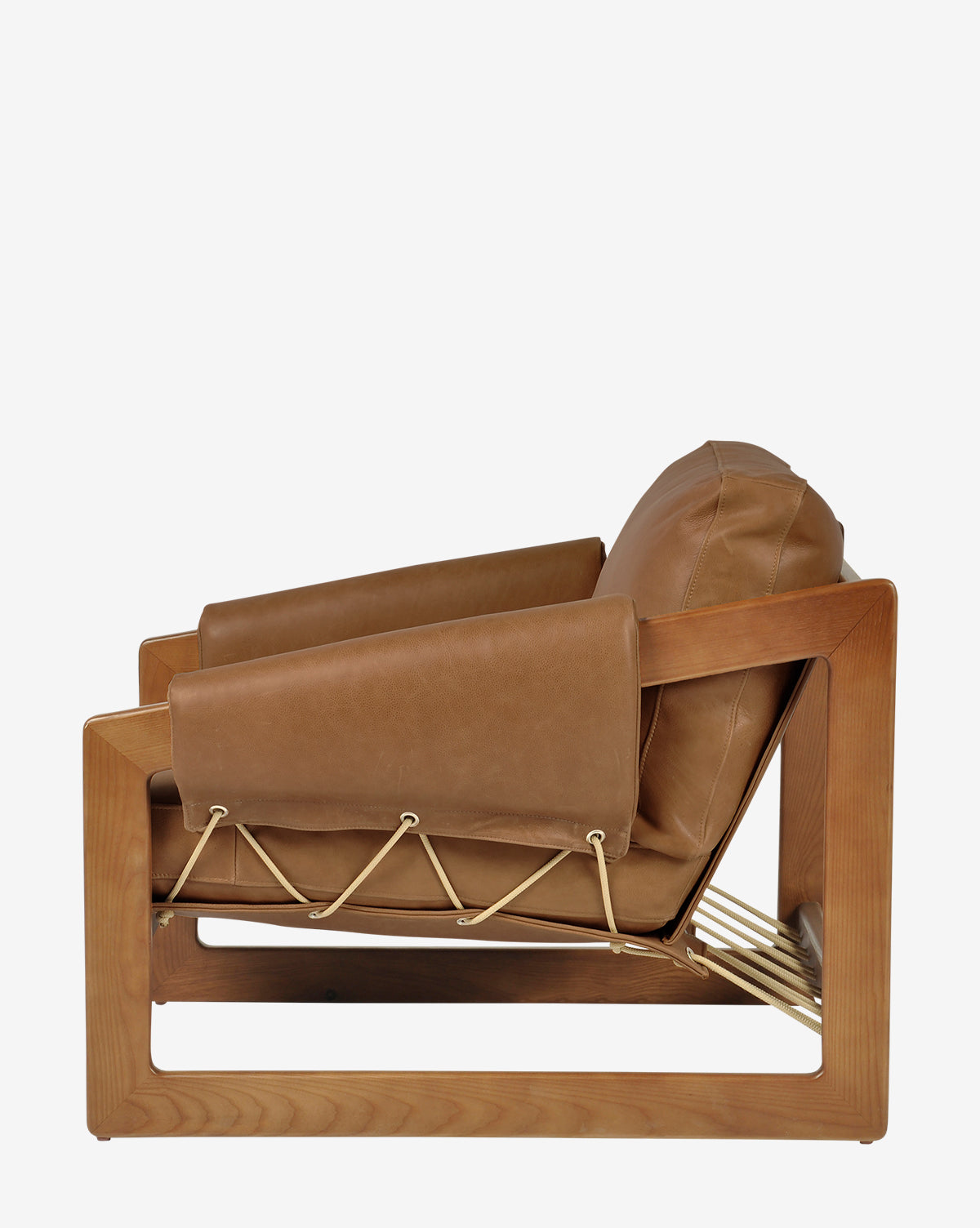 Side view of the Barker Lounge Chair, a modern armchair with a wooden frame, tan top-grain leather cushions, and rope accents inspired by classic midcentury sling seating, by Vendixs