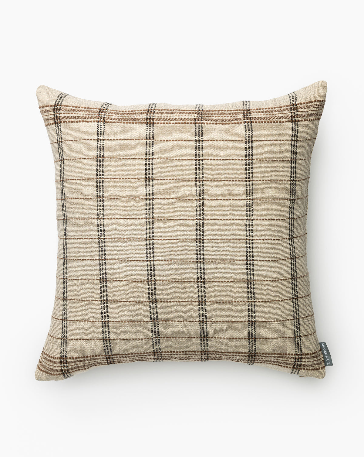The Benedict Pillow Cover features a beige base with brown and dark gray plaid, seen from above on a white background. A small fabric tag is visible at the bottom right, adding stylish accent to any home décor, by McGee & Co.