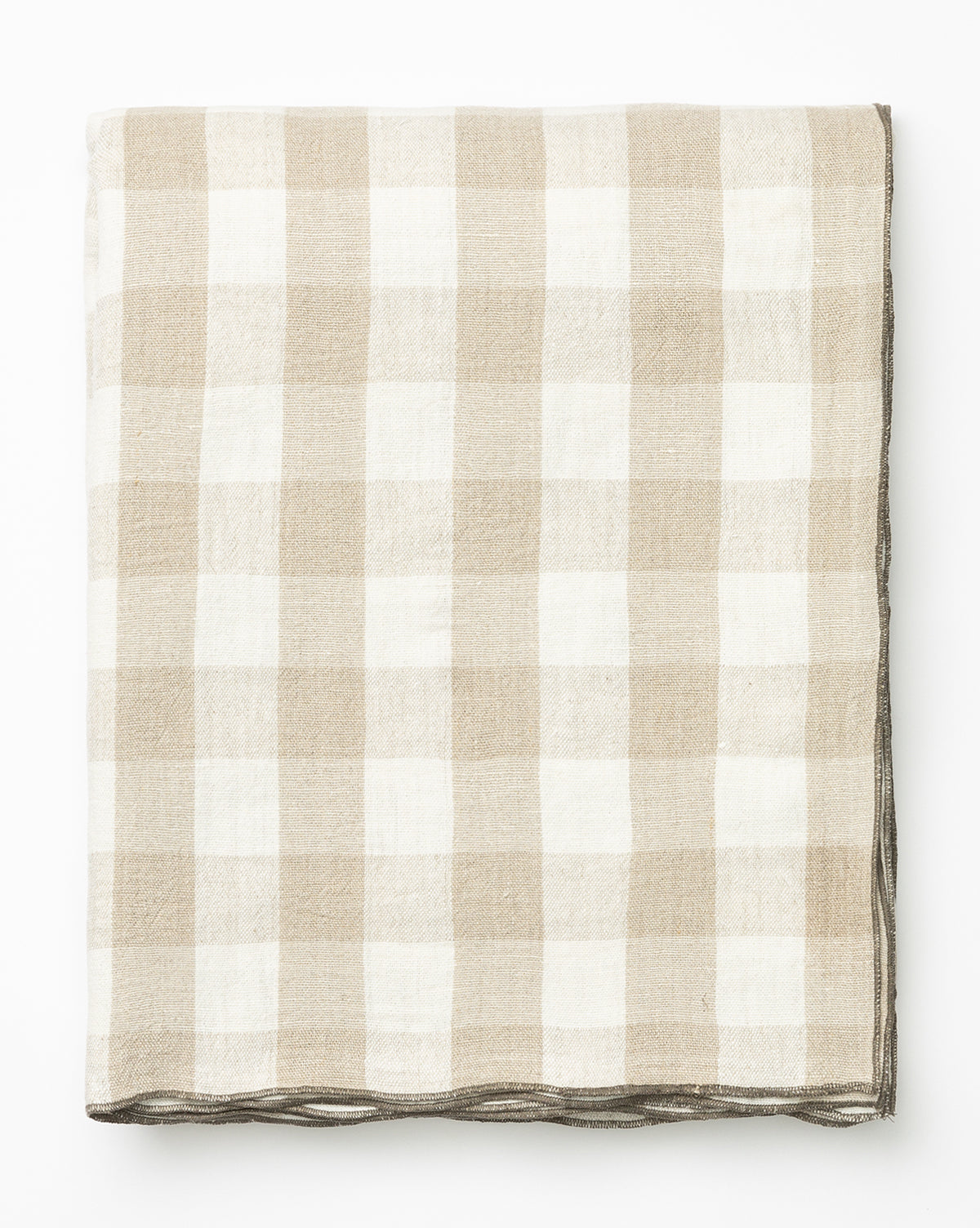 The Charlie Check Tablecloth, neatly folded, features a beige and white gingham pattern and is displayed on a white background by McGee & Co.