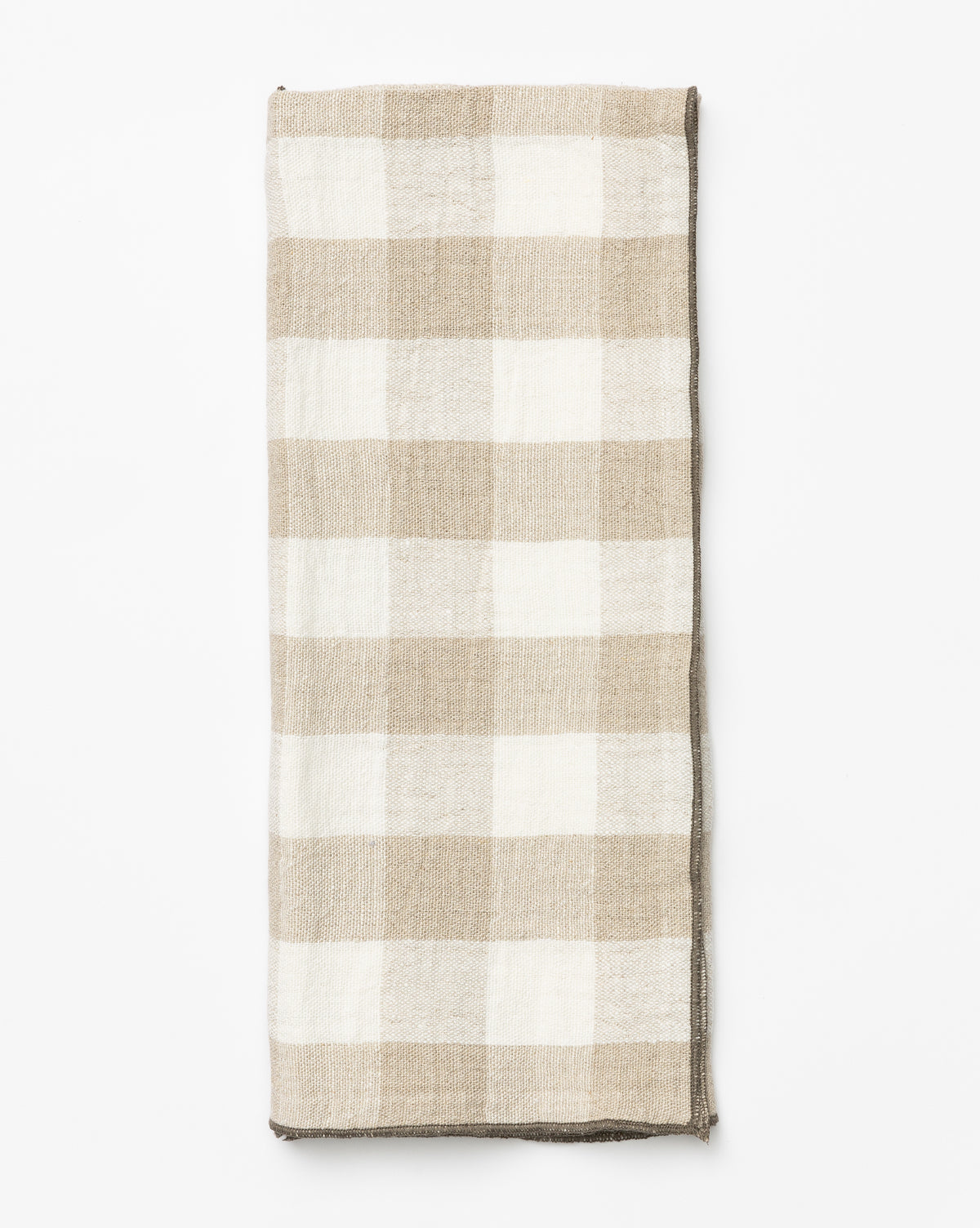 The Charlie Check Tea Towel, featuring a folded beige and white checkered linen pattern, is displayed on a white background—ideal for elegant table settings, by Vendixs