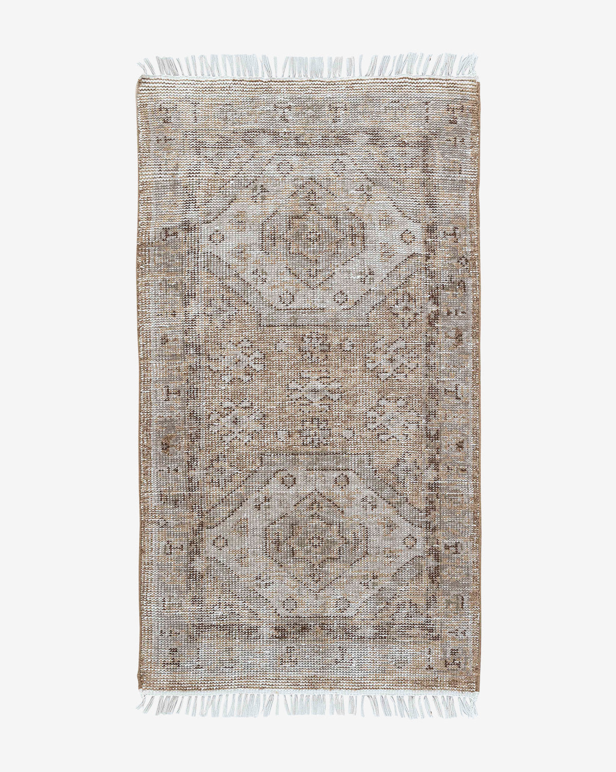 The Charlot Hand-Knotted Rug is a rectangular, handmade piece featuring a faded geometric and floral pattern in muted beige, brown, and gray, finished with short white fringe on both ends for vintage style, by Vendixs