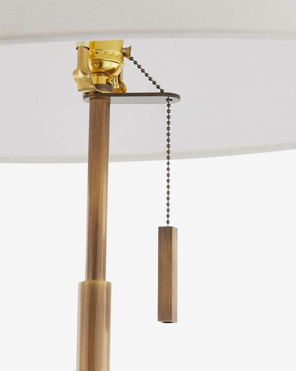 A close-up of the Clic Floor Lamp’s pull chain highlights its brass fixture, brown wooden pole, and cylindrical wooden pull beneath an off-white linen shade, by Vendixs