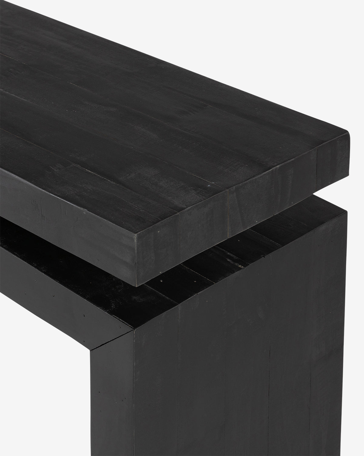 A close-up of the Colter Console Table—a modern black wooden piece with clean lines, crafted from reclaimed wood—showing its edge and corner against a white background, by Vendixs