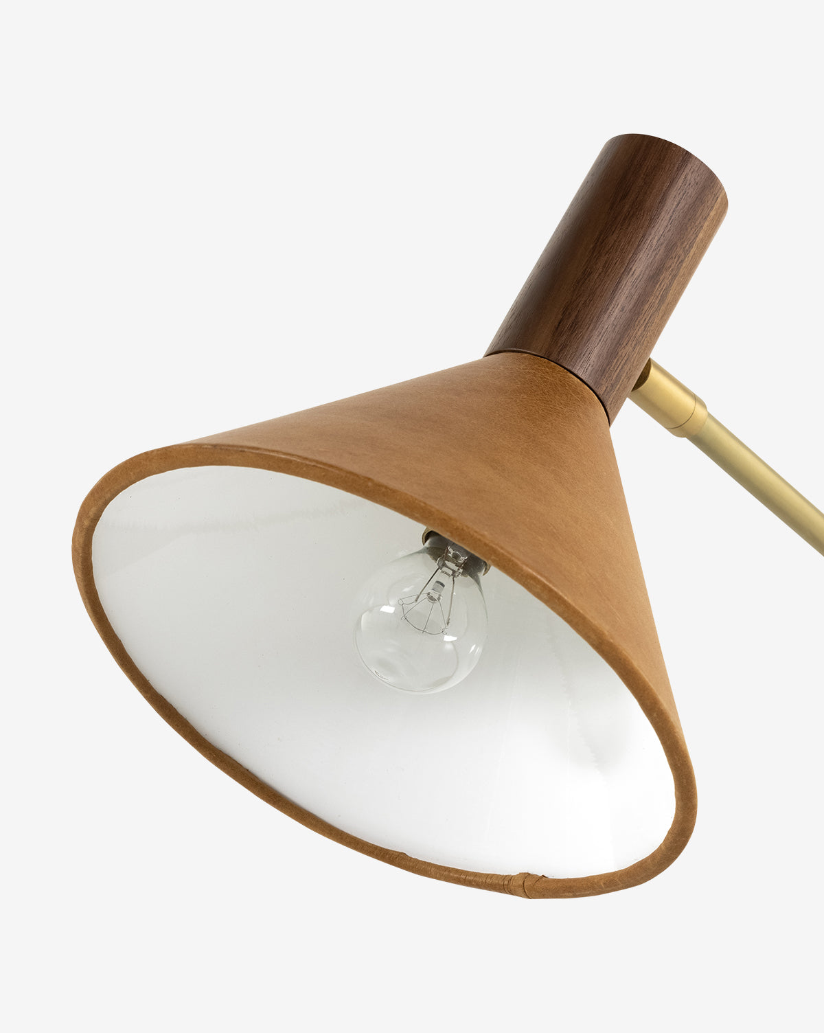 A close-up of the Cullen Task Lamp featuring a conical top-grain leather shade, white interior, exposed bulb, wooden fixture, and brass arm on a plain white background, by Vendixs