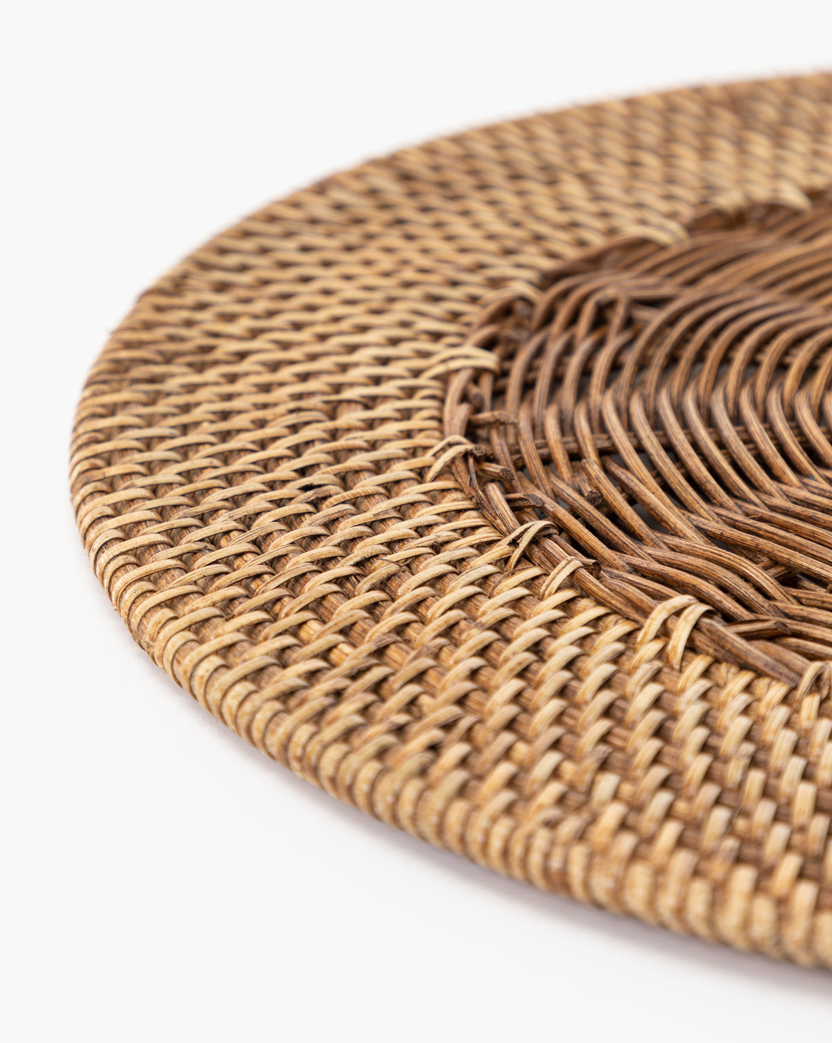 Close-up of the Davin Placemat, a round wicker mat with a braided pattern and contrasting brown center and lighter edge on a white background—ideal for adding a coastal touch to your table setting, by Vendixs