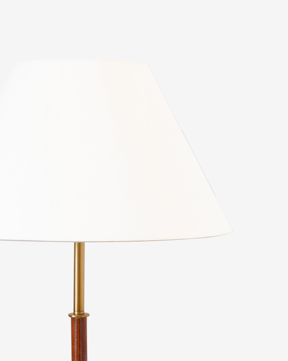 A close-up of the Elijah Floor Lamp with a white cone-shaped shade, brass pole neck, and brown base with leather accent, shown against a plain white background by Vendixs