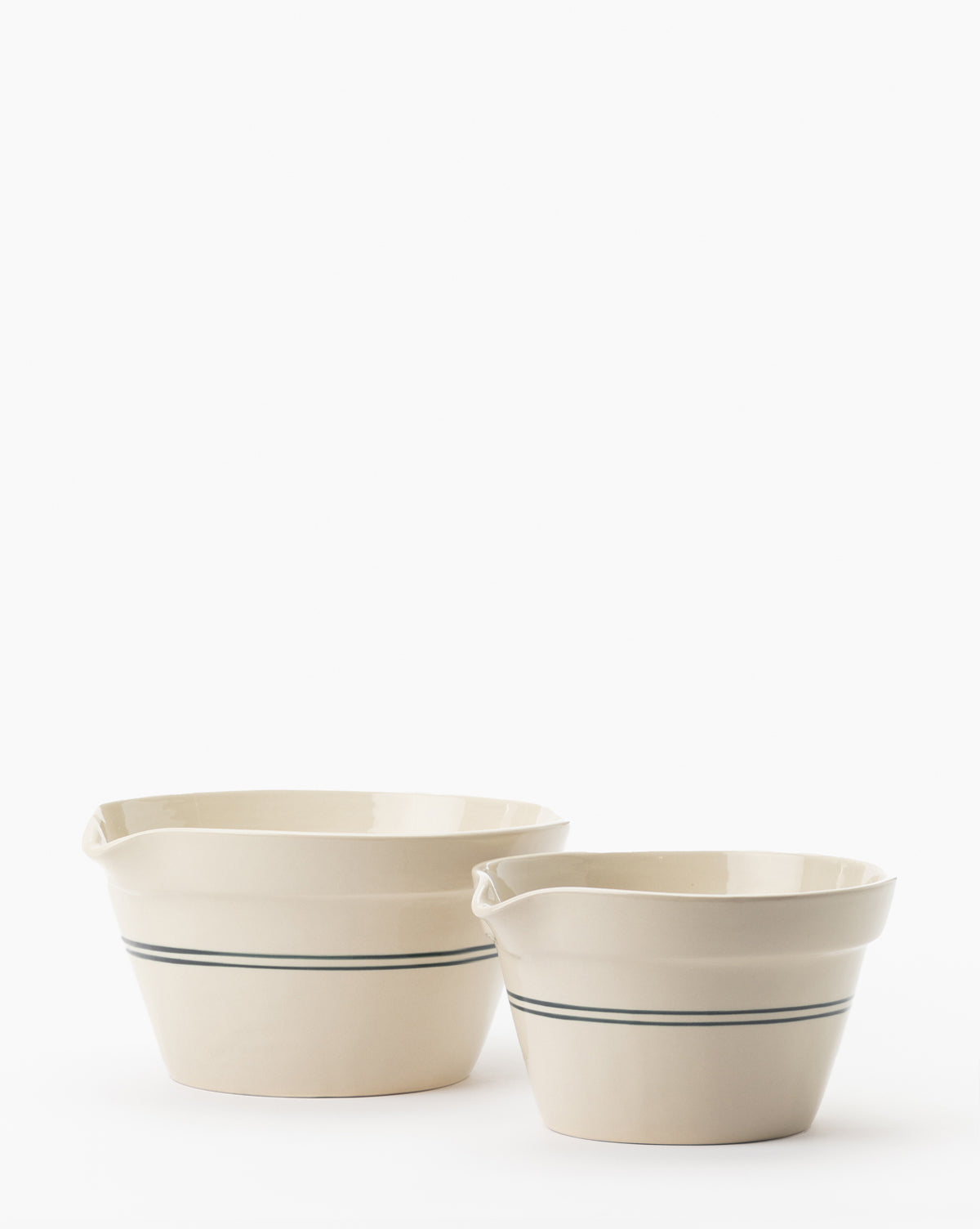 The Everett Mixing Bowl, a cream-colored ceramic bowl with pouring spout and thin blue stripe, is shown side by side with another on a white background by Vendixs