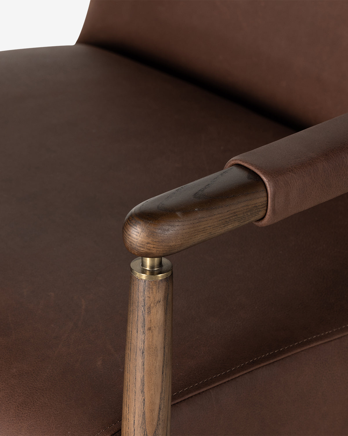 Close-up of the Gaston Lounge Chair, showcasing its top grain leather upholstery, solid ash frame, and brass detailing that highlight the leather’s rich texture and the smooth finish of wood and metal, by Vendixs