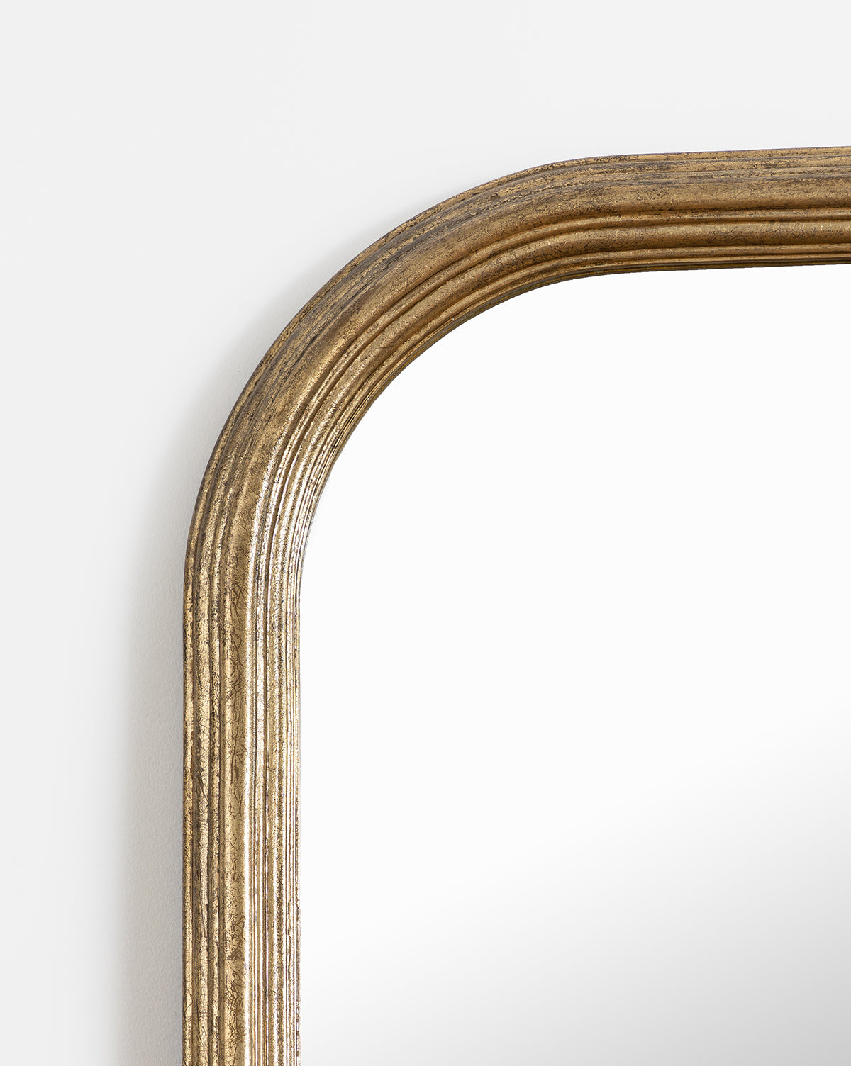 Close-up of the top left corner of the Giada Floor Mirror, featuring a rectangular design with an elegant gold ridged frame and rounded edges, set against a plain white background, by Vendixs
