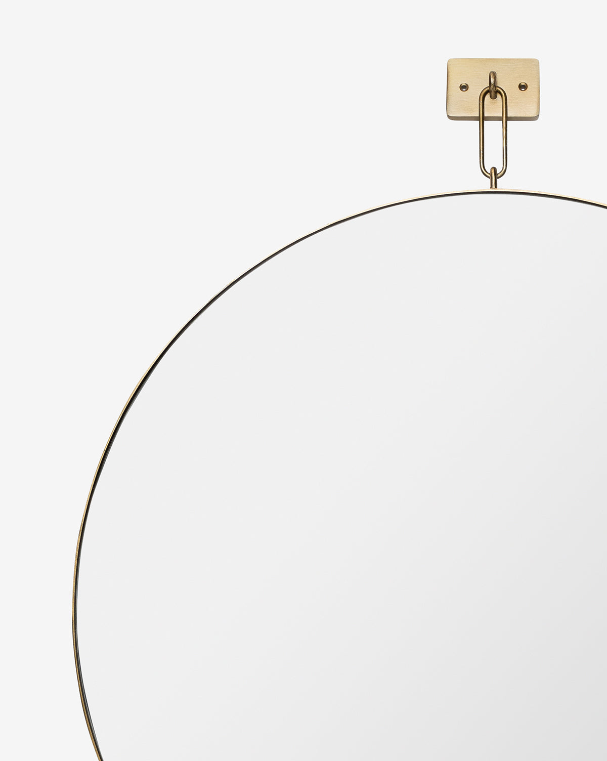 The Haven Wall Mirror, featuring a thin stainless steel frame, hangs from a gold wall mount and chain against a plain white background. Only the top part of this modern, elegant mirror is shown in the image, by Vendixs