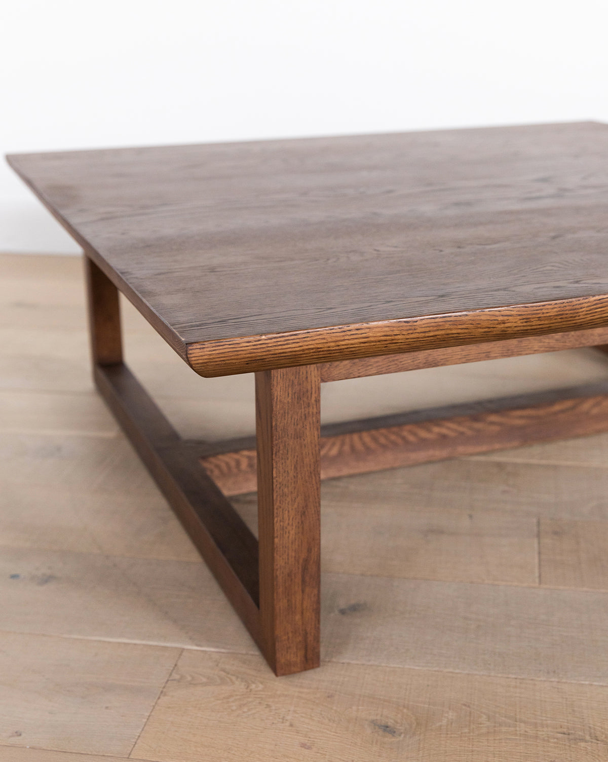 The Herrin Coffee Table boasts a rectangular solid oak top and sturdy square legs, bringing modern style to any space, especially on light wood floors with a white wall backdrop, by Vendixs