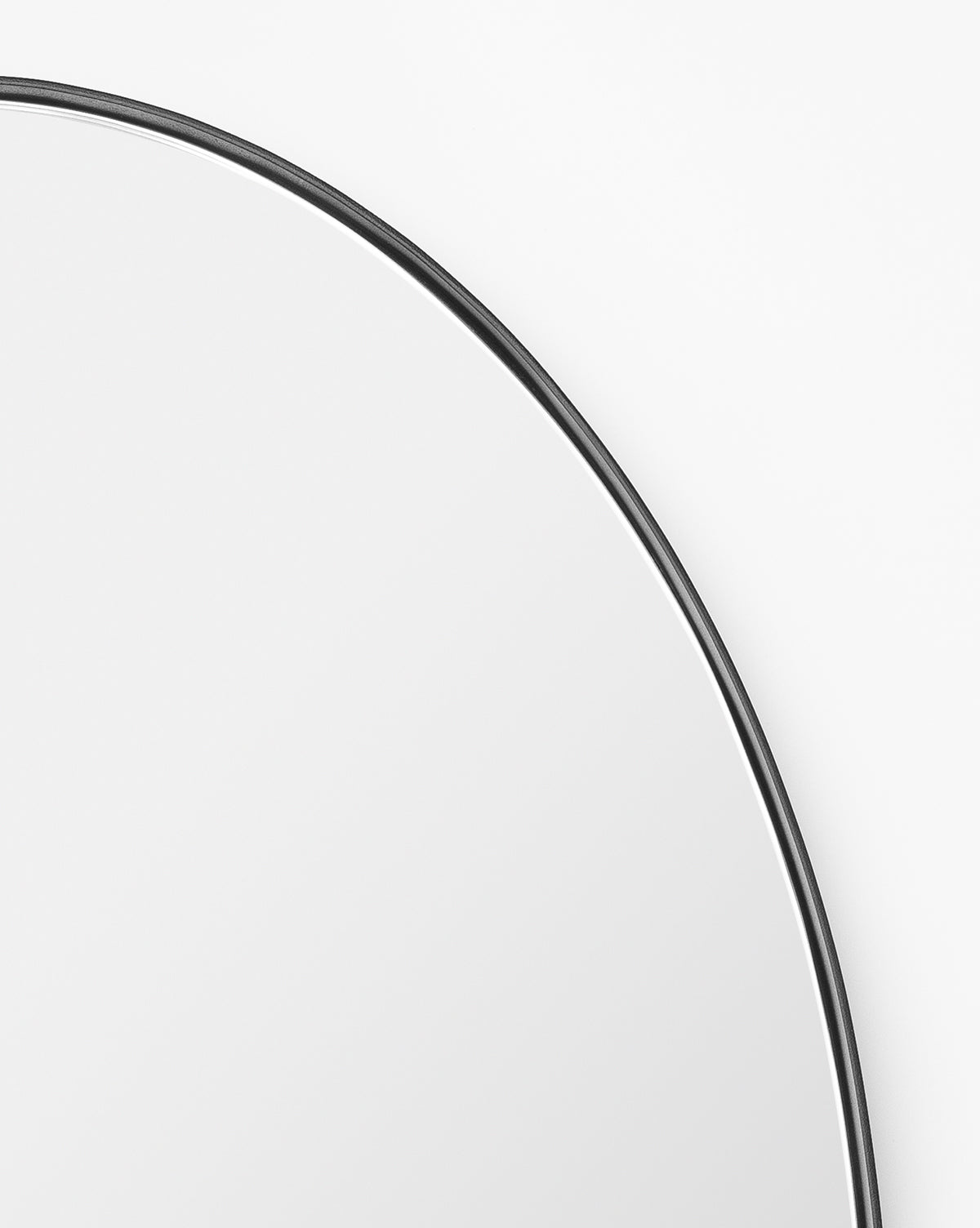 A close-up of the Hogan Oval Mirror showcases its sleek, thin stainless steel frame, with only the upper section visible against a plain white background, by Vendixs
