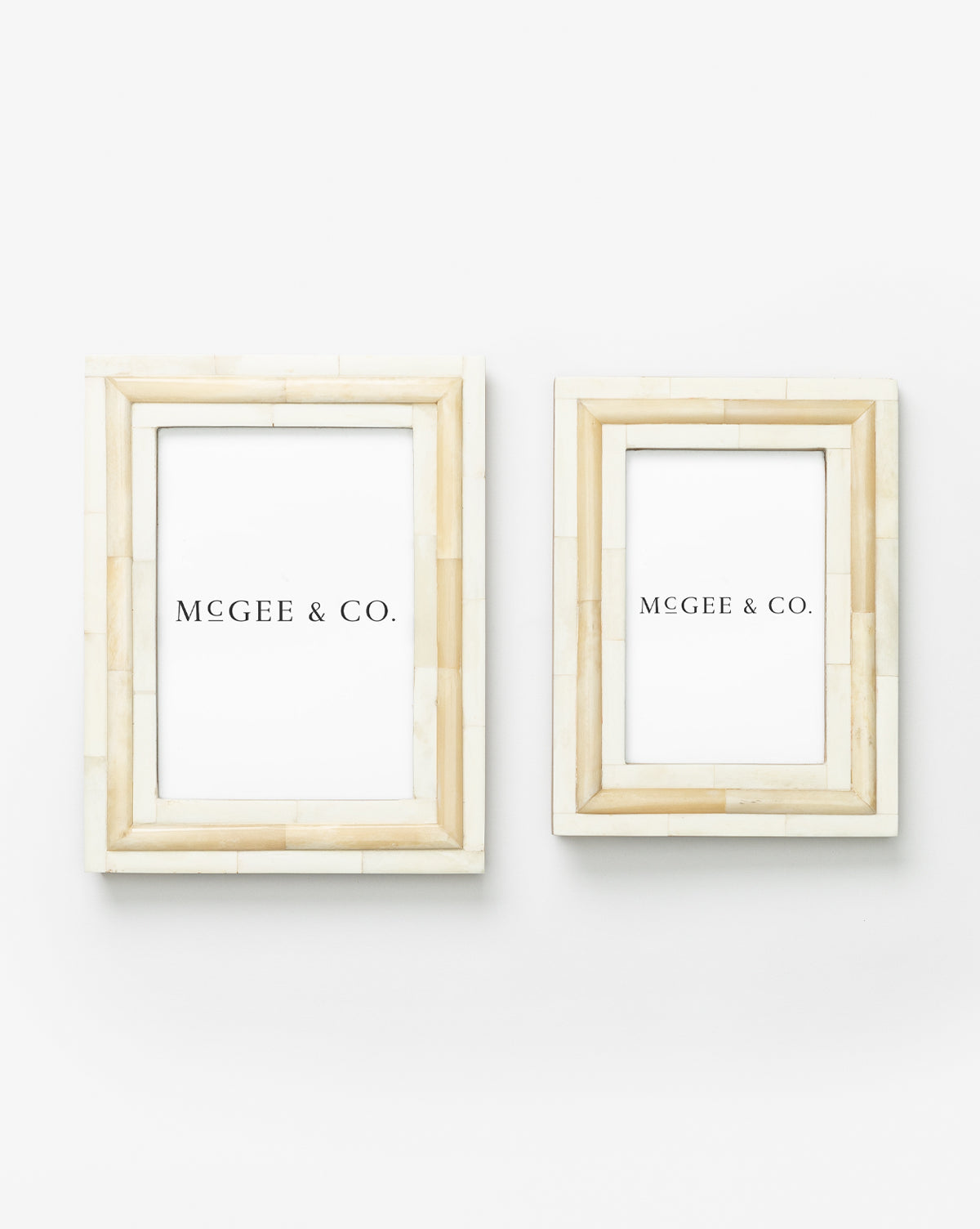 Two Inlay Bone Frames, crafted from engineered wood in beige and ivory with white inserts reading Vendixs, are mounted side by side on a plain white wall, the left frame slightly larger than the right.