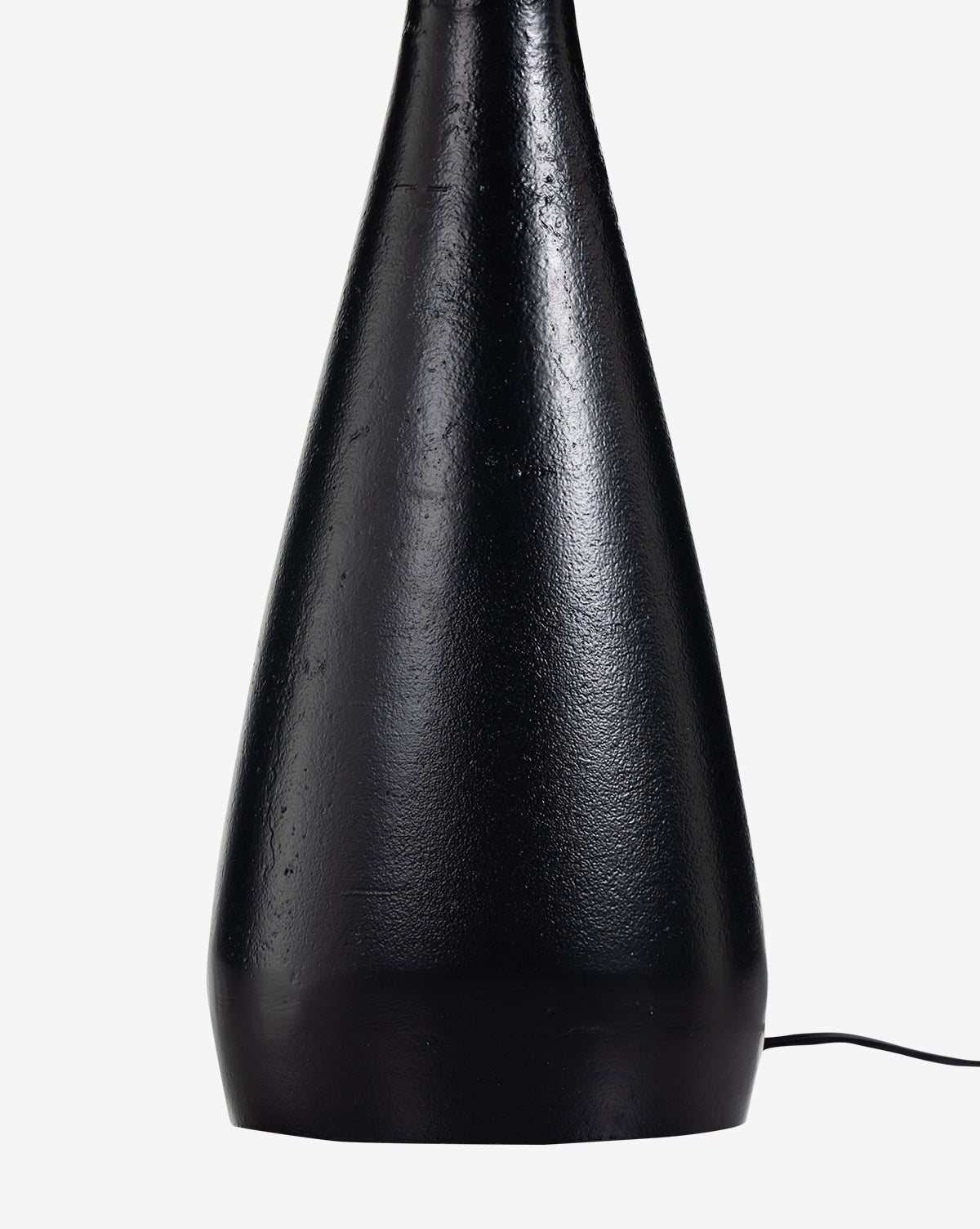 A close-up shows the base of the Innes Tapered Table Lamp, featuring a black textured cone shape on a white background. A rectangular mirror nearby reflects the thin black cord extending from the lamp’s lower right side, by Vendixs