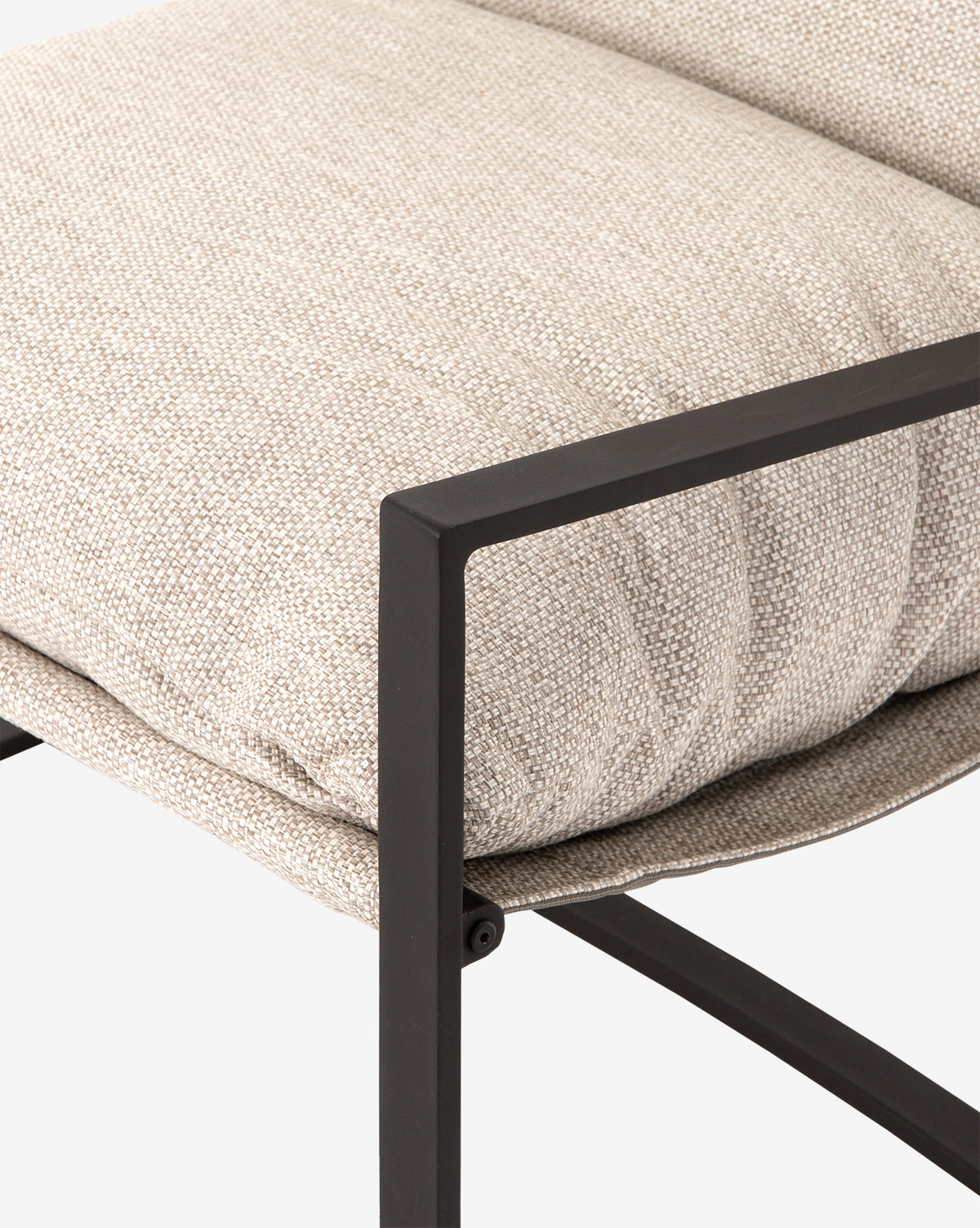 Close-up of the Ismay Sling Chair featuring a textured beige removable cushion and a sleek black metal frame with angular lines, set against a plain white background by McGee & Co.